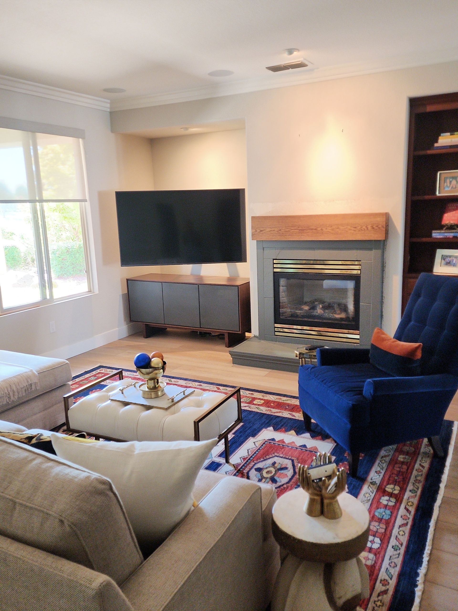 Living room with a fireplace, TV, blue chair, rug, and white sofa.