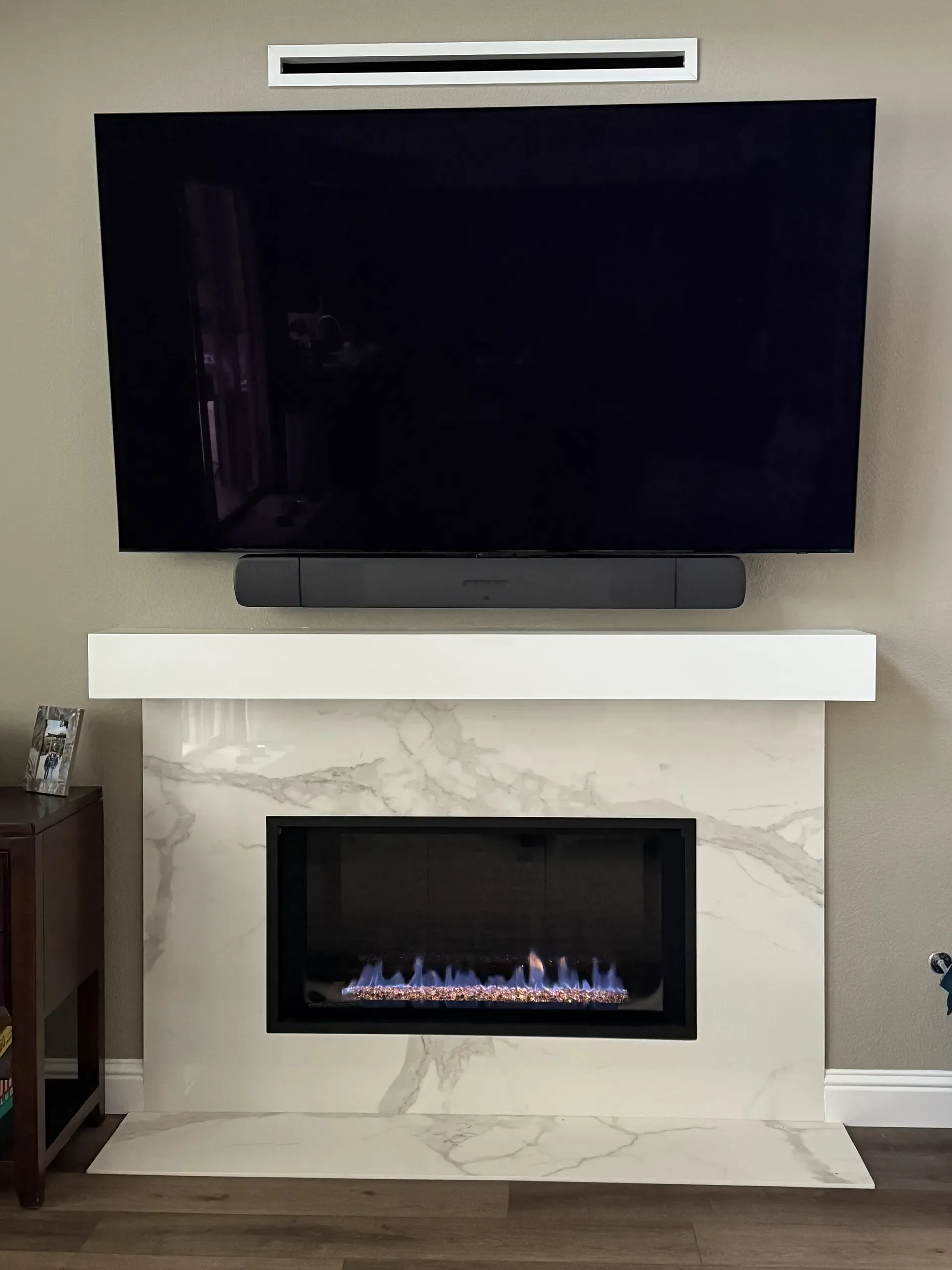 Modern fireplace with TV and soundbar above, set in a room with light-colored walls and flooring.
