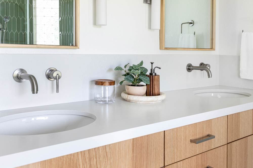 Double bathroom vanity with wood cabinets, white countertop, and wall-mounted faucets.