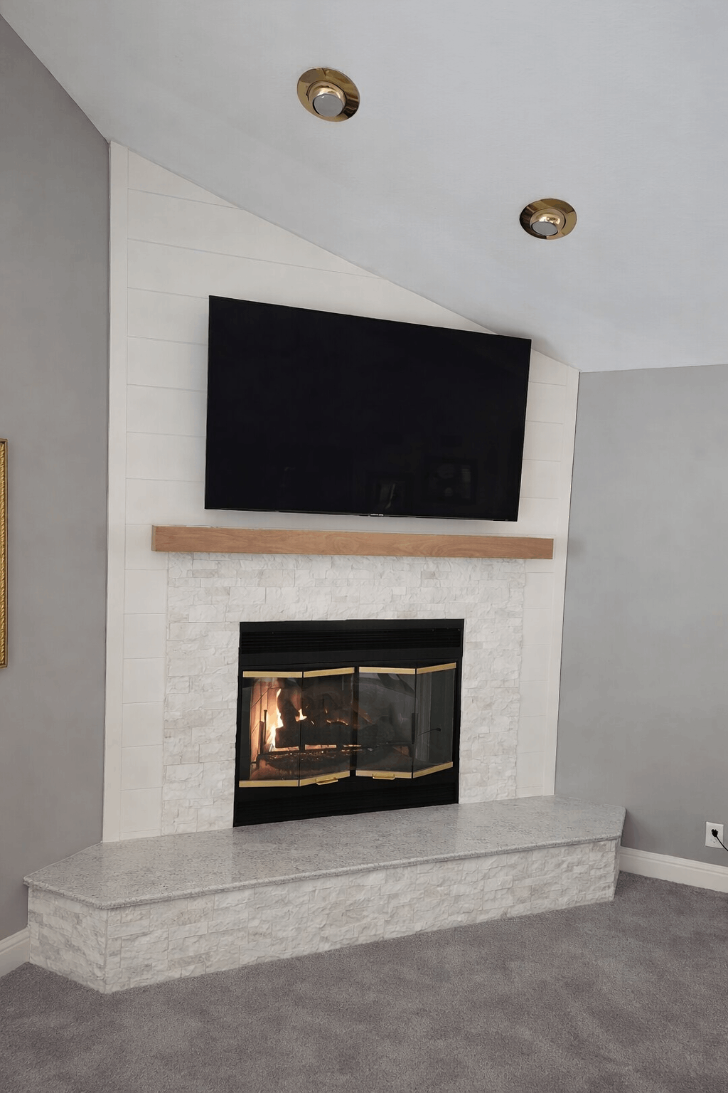Fireplace with TV above, tiled surround, and gray walls, built-in in a corner.