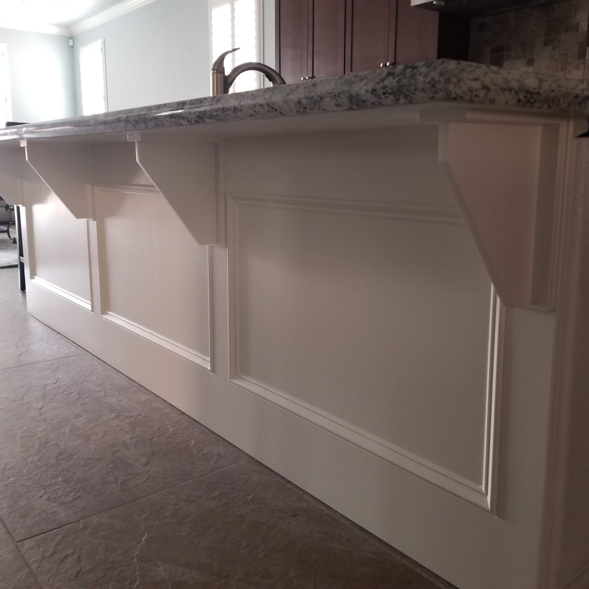 White kitchen island with countertop, decorative panels, and supports.