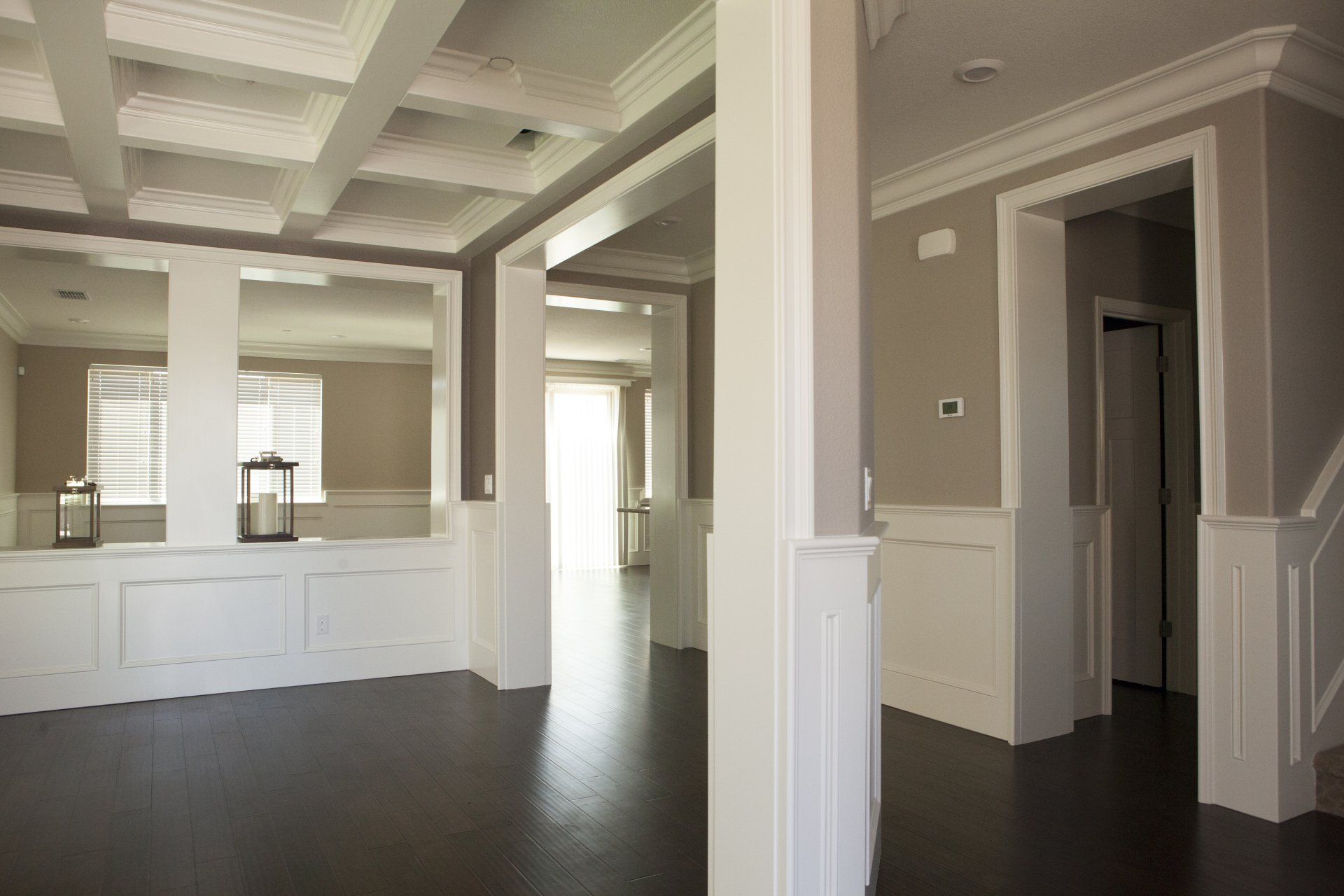 Interior view of a home with white trim, brown floors, beige walls, and decorative ceiling beams.