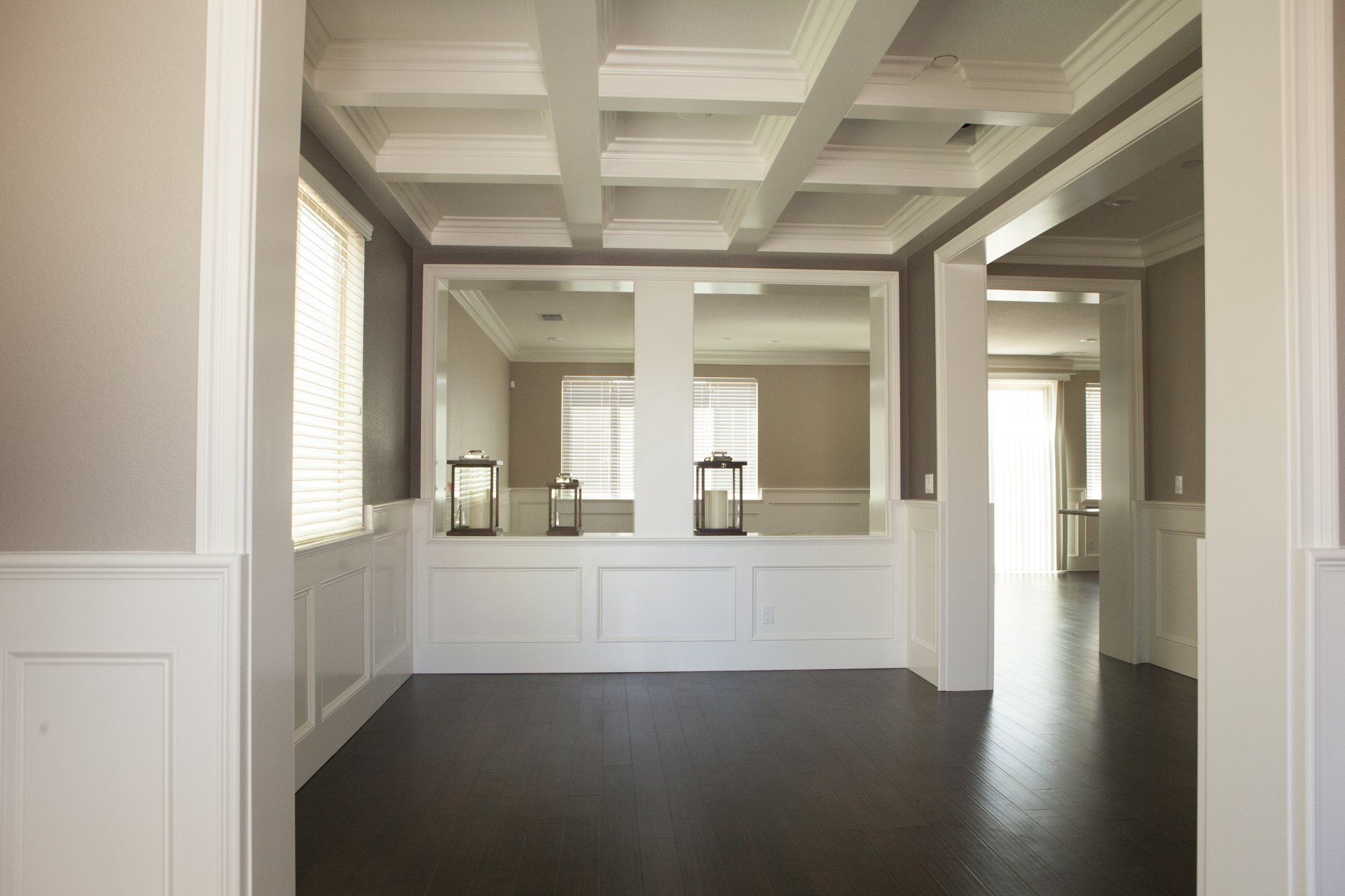 Empty room with dark wood floor, white trim, and a coffered ceiling.