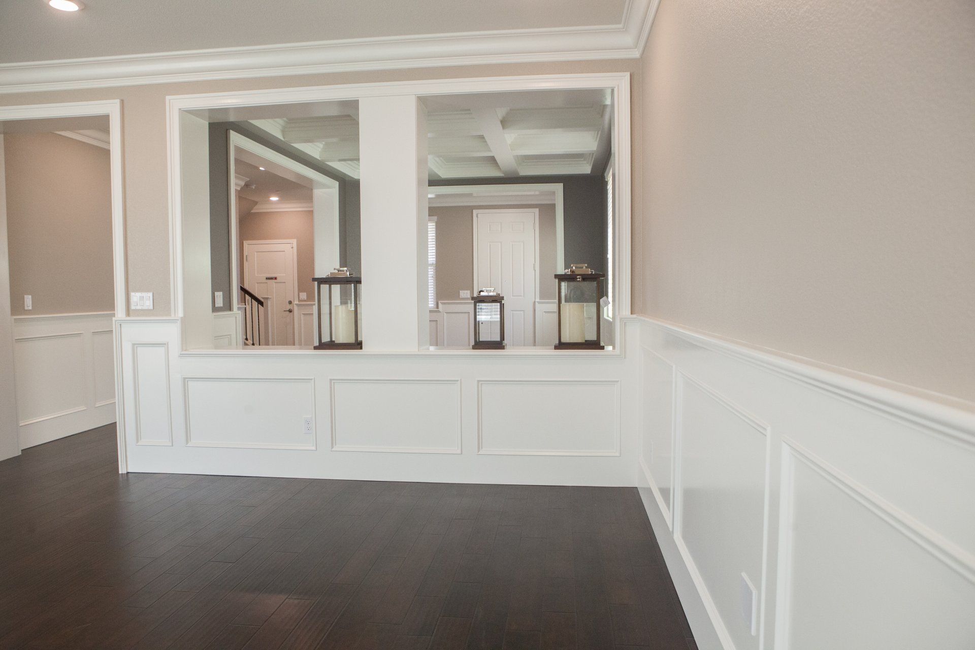 Hallway with white paneling, mirrors, and dark wood floors.