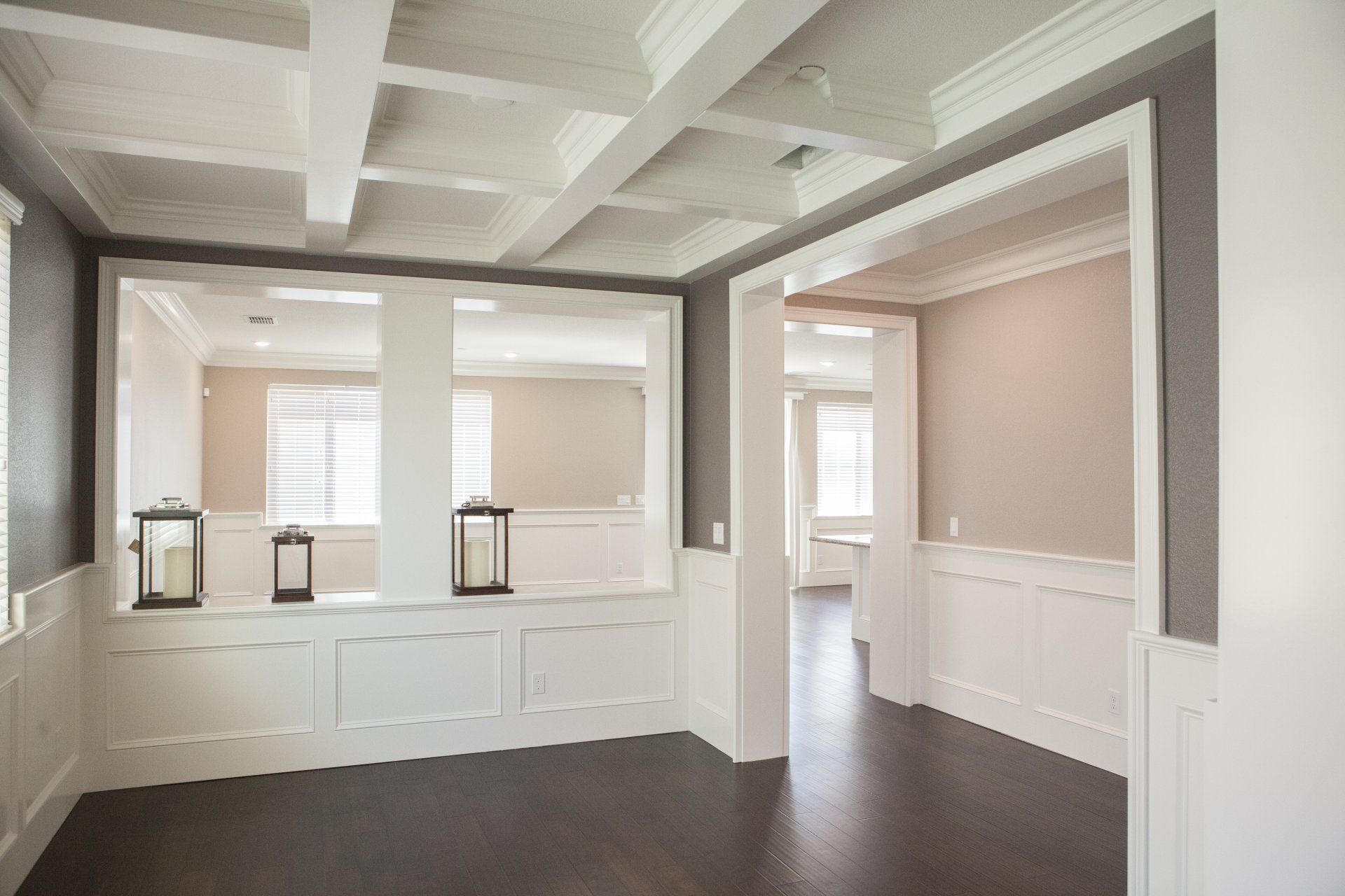Elegant dining room with dark wood floors, white paneling, and a large mirror.
