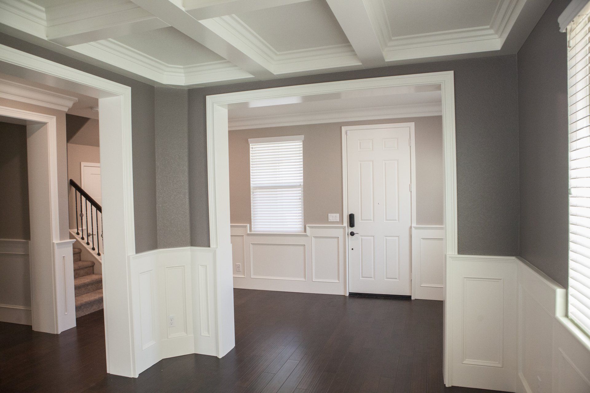 Interior view of a gray and white room with dark hardwood floors, wainscoting, and a coffered ceiling.