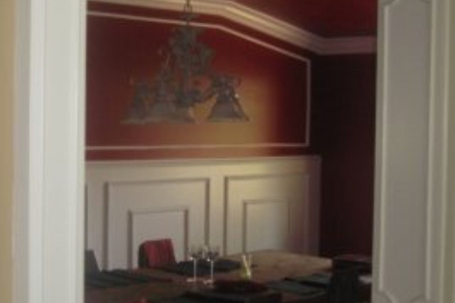 Dining room with red walls, white trim, chandelier, and table.