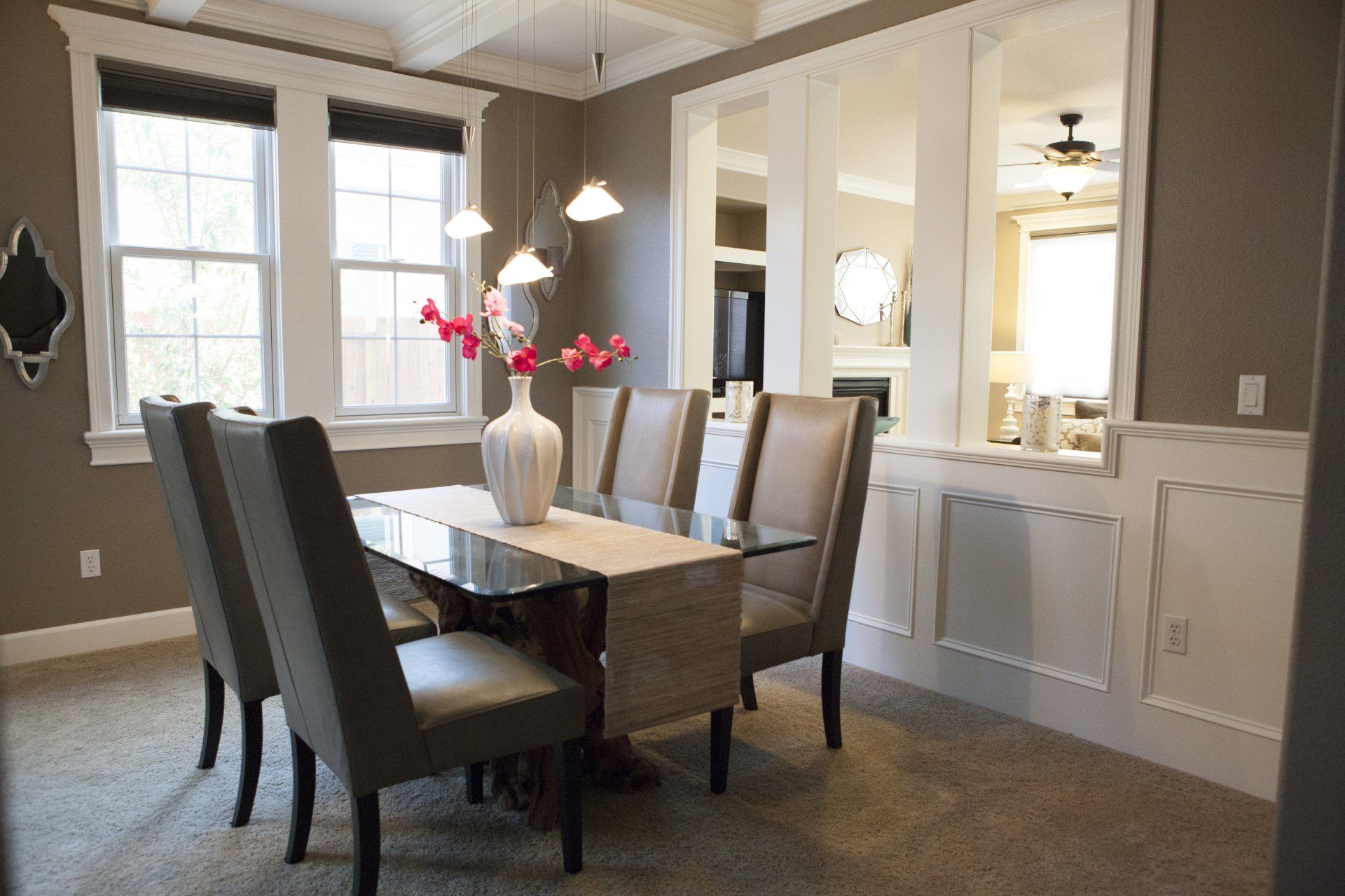 Dining room with table and chairs, windows, and mirrors; neutral colors.