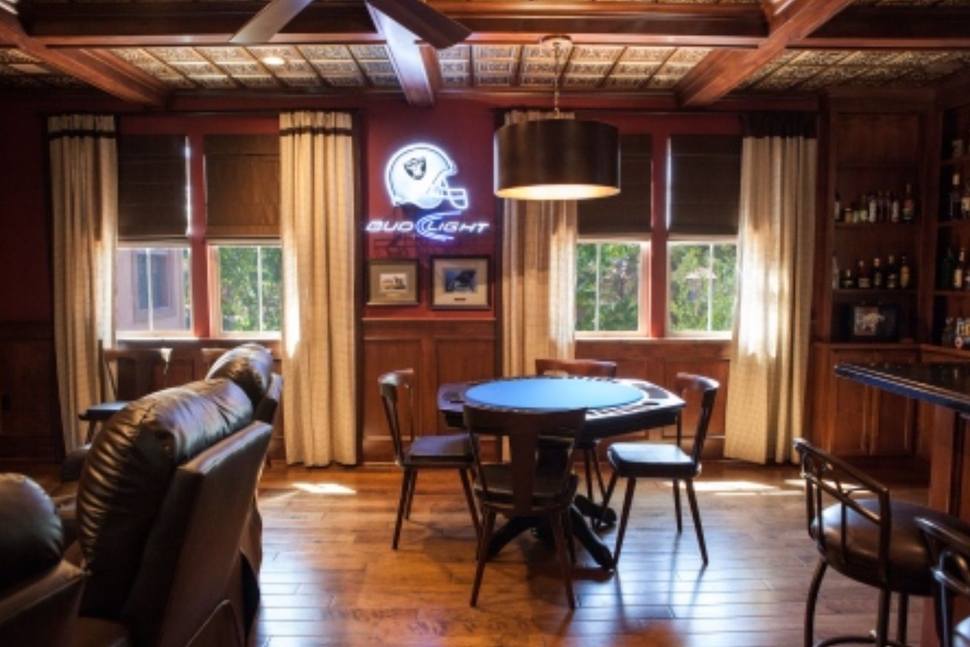 A game room with a round table, chairs, a sofa, and a neon sign for the Los Angeles Rams.