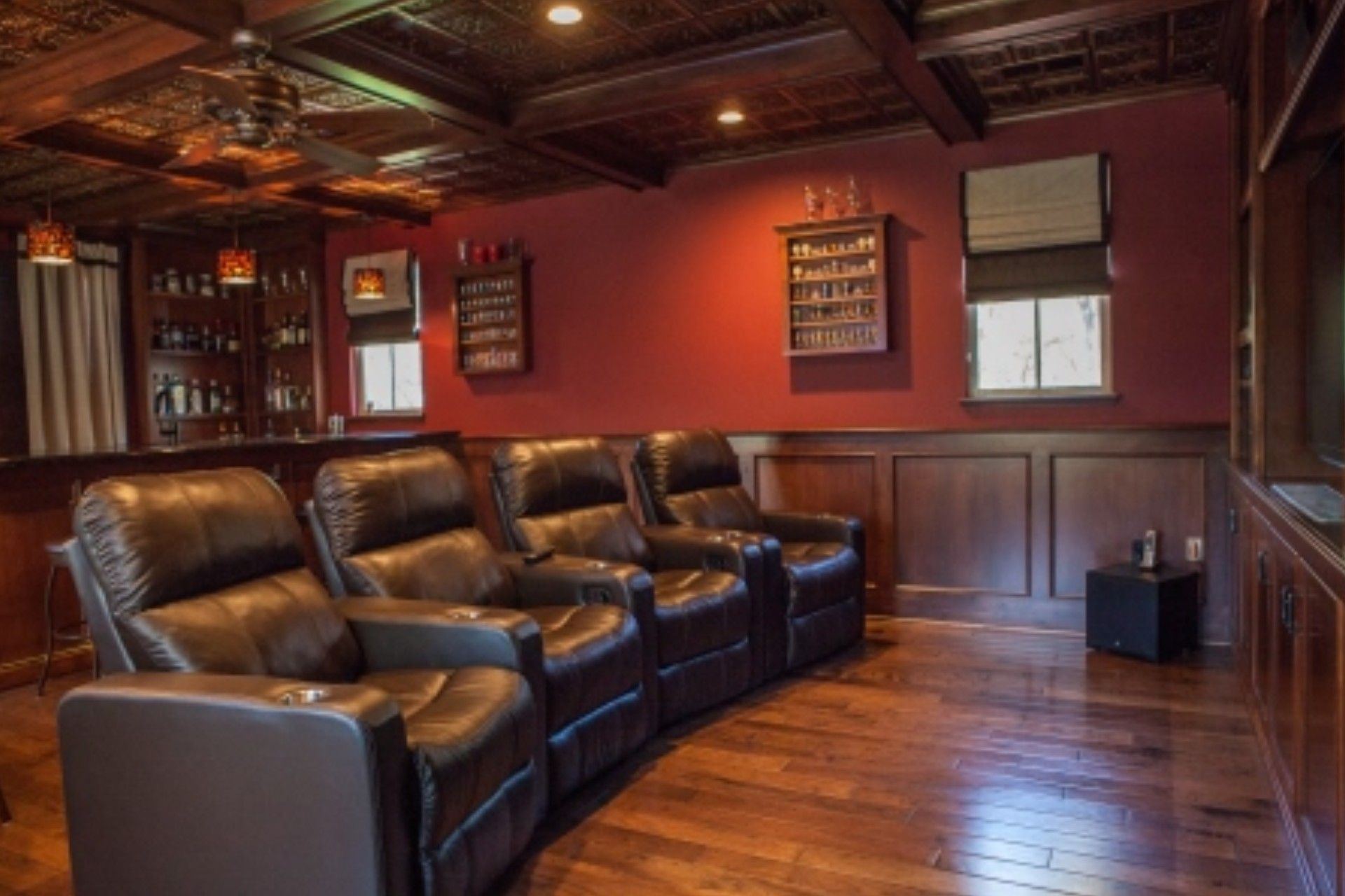 Home theater with leather recliners, a bar, and a red accent wall.