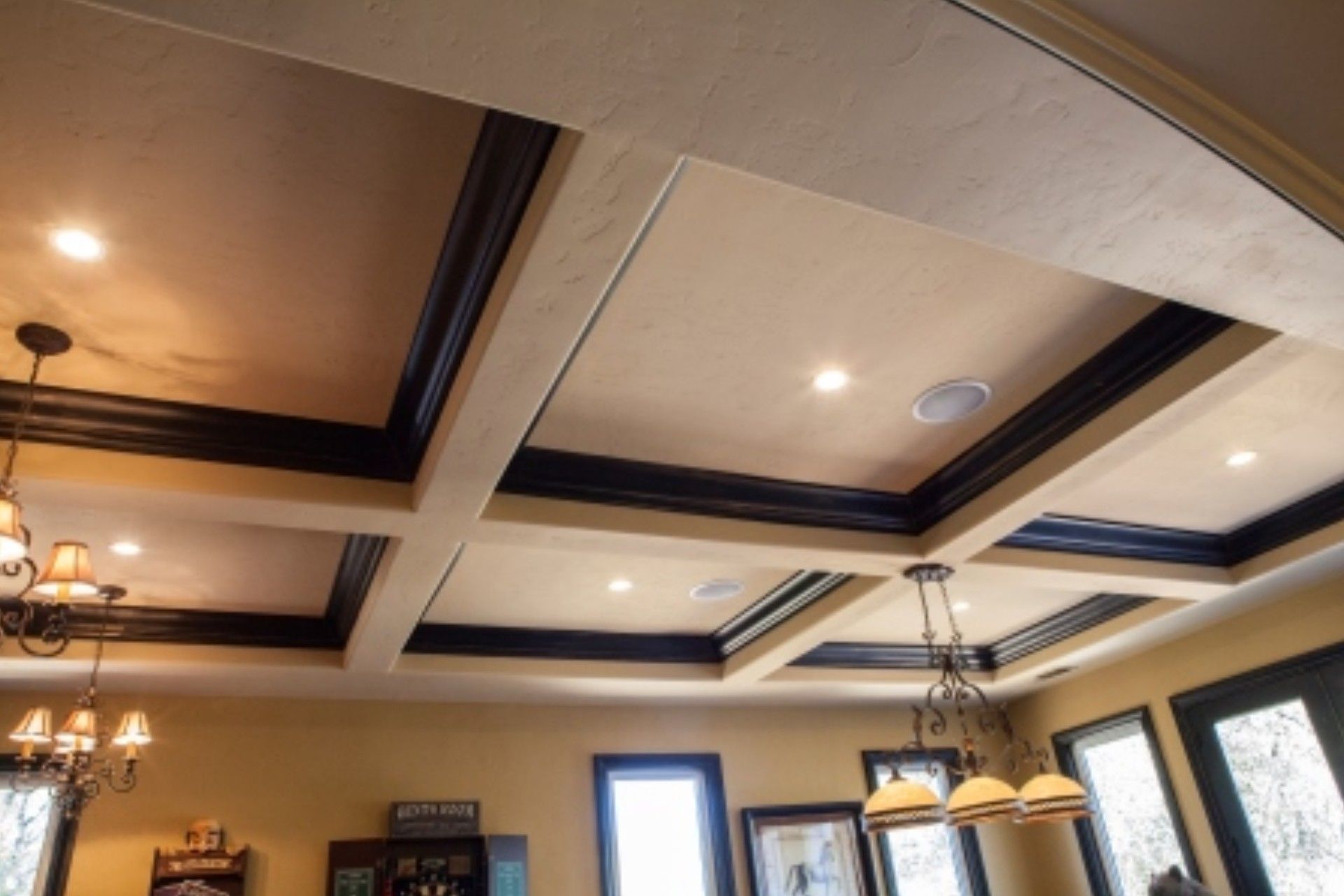 Beamed ceiling with recessed lighting, dark trim, and light-colored panels.