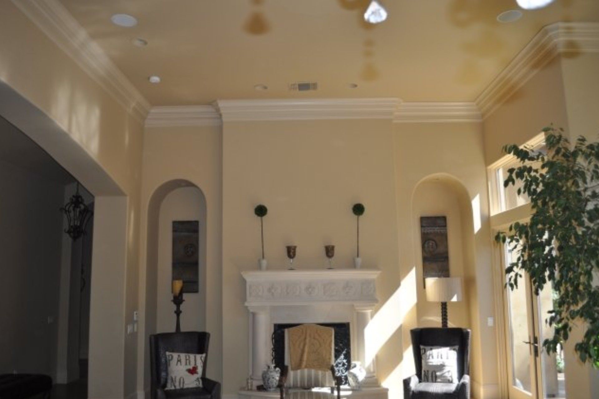 Living room with fireplace, arches, white crown molding, and tall ceilings.
