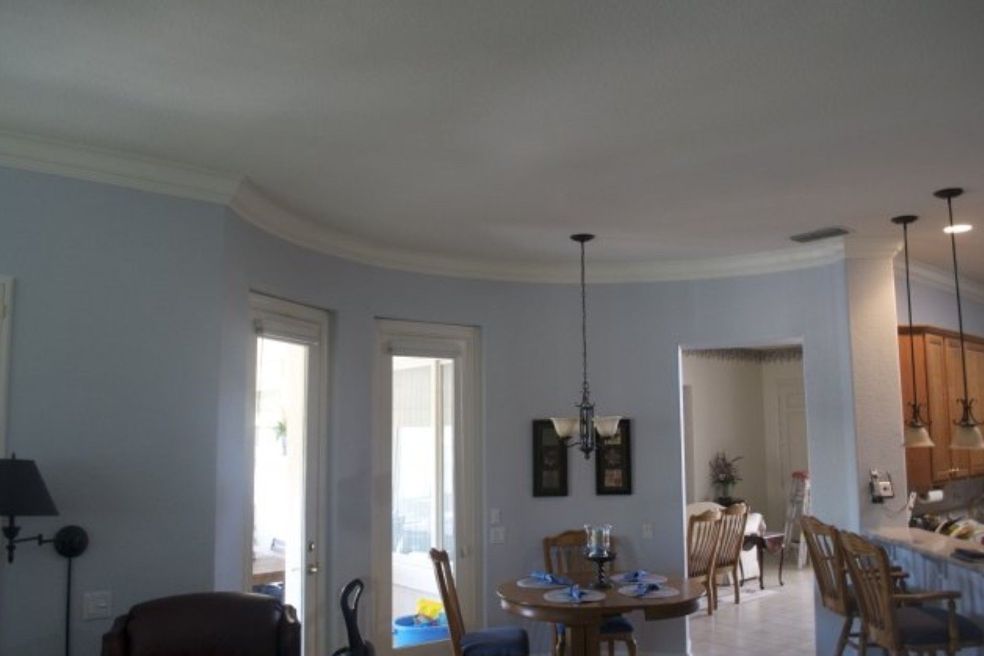 A blue-walled interior with curved ceiling detail, French doors, a dining area, and kitchen visible.