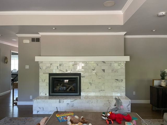 Fireplace with light gray walls, white mantel, and gray and white tile. Living room setting.