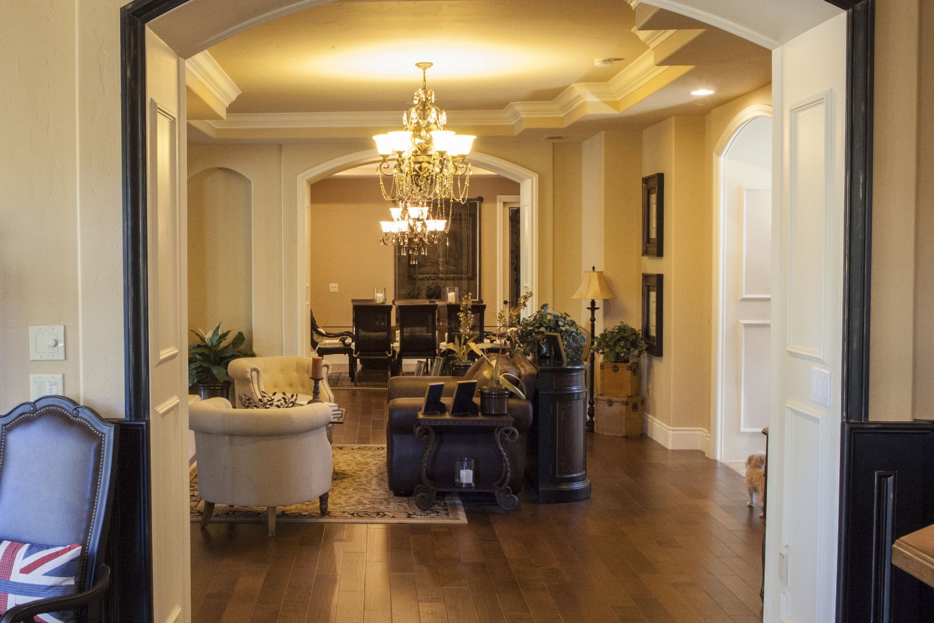 Elegant interior, arched doorways lead to a living area with chandelier, seating, and dark wood floors.