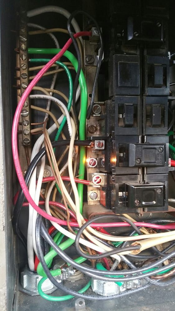 Open electrical breaker box with various colored wiring connected to a central bus bar and multiple circuit breakers.