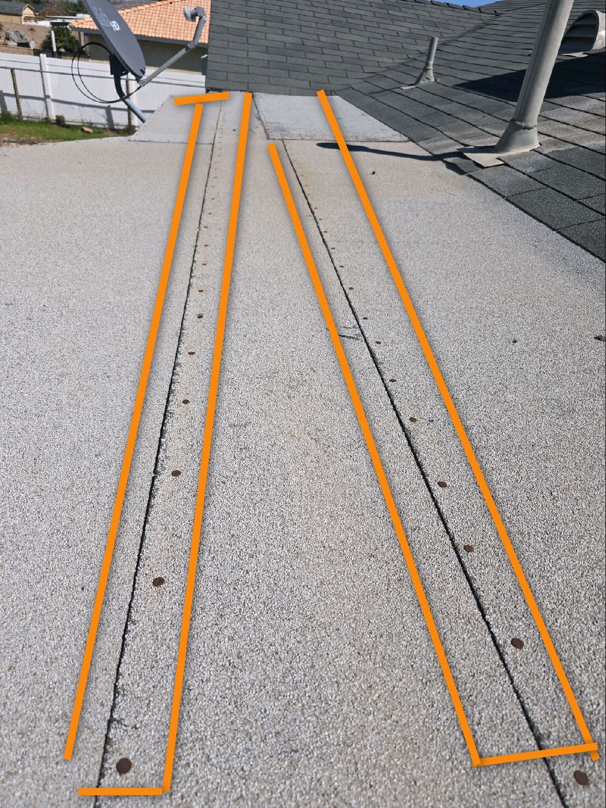 A low-slope roof section features two rectangular areas outlined in orange to highlight seam repairs on the textured surface.