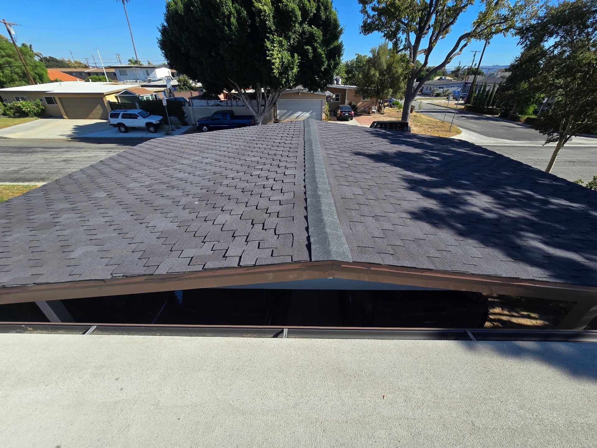 View from rooftop along shingled ridge over a suburban street on a sunny day