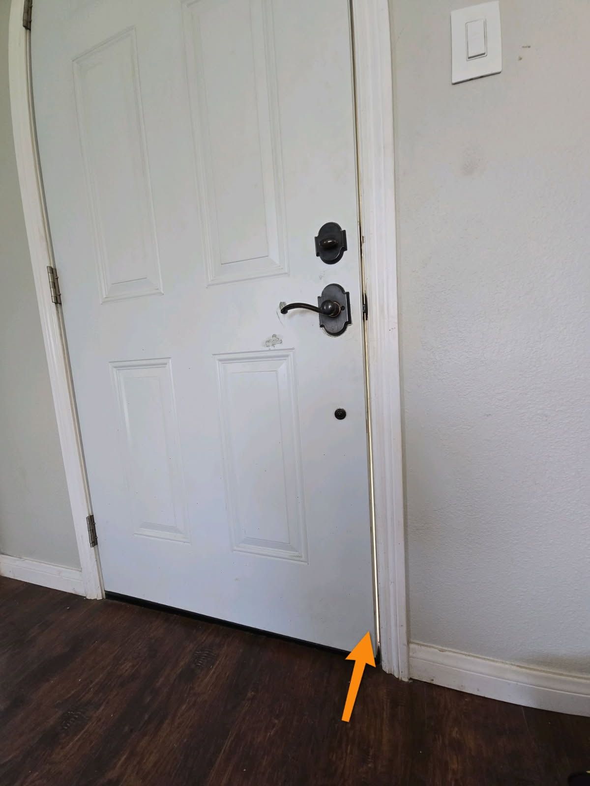 An orange arrow points to a gap in the white door frame where weather stripping is peeling away from the door.