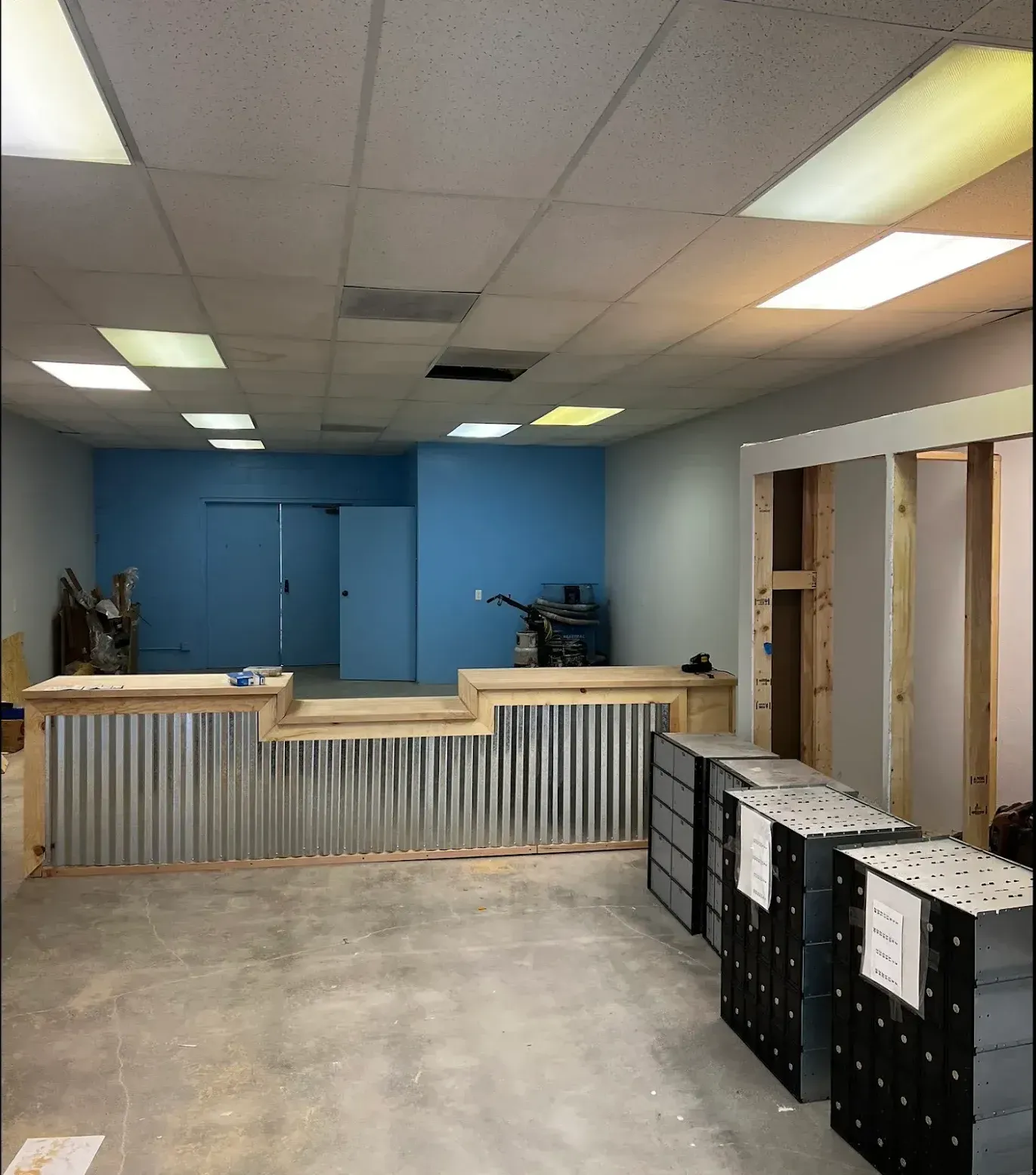 Construction scene featuring a wooden reception desk with corrugated metal siding in a room with a blue accent wall.
