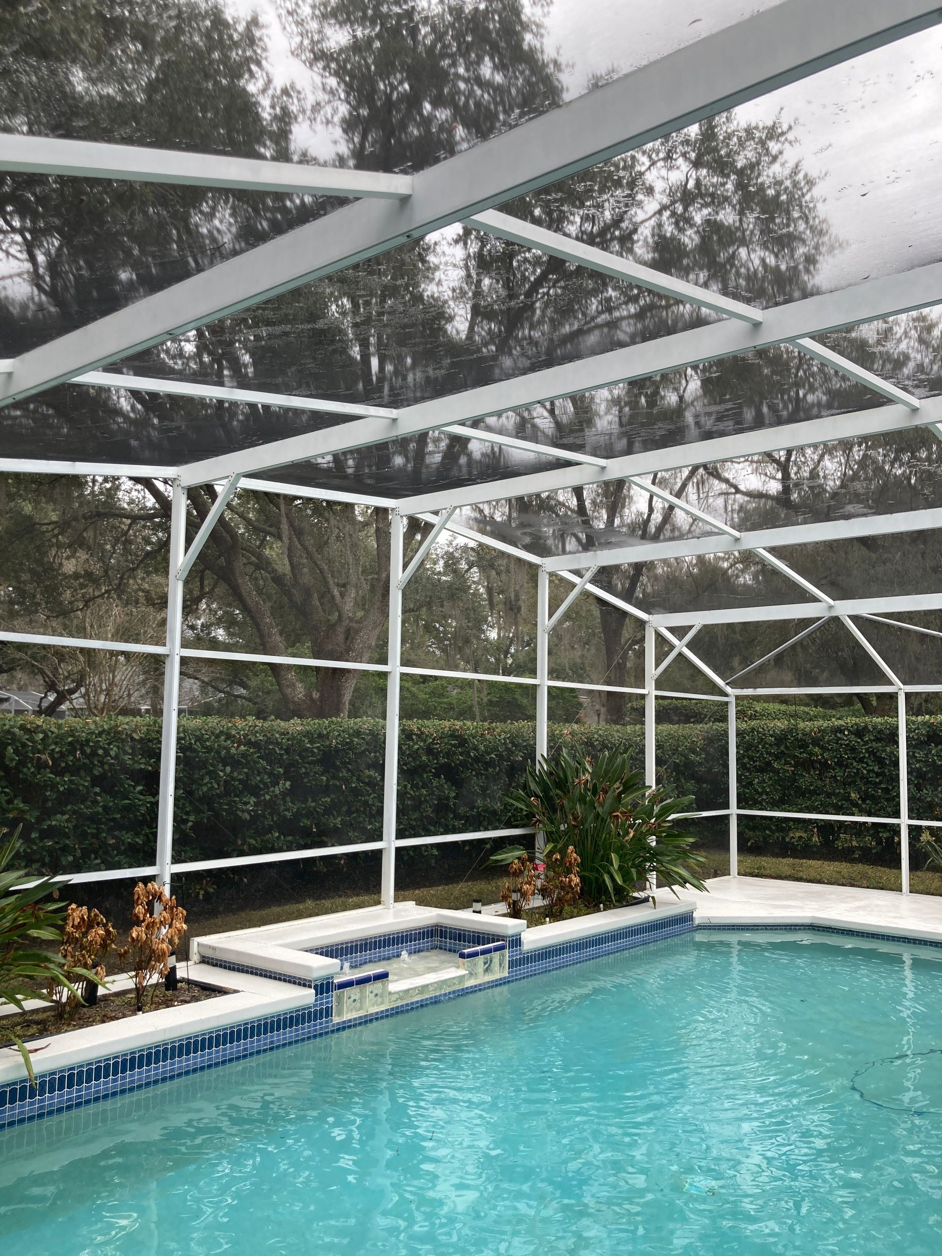 Screened-in backyard pool with turquoise water, white deck, and snowy trees beyond the enclosure