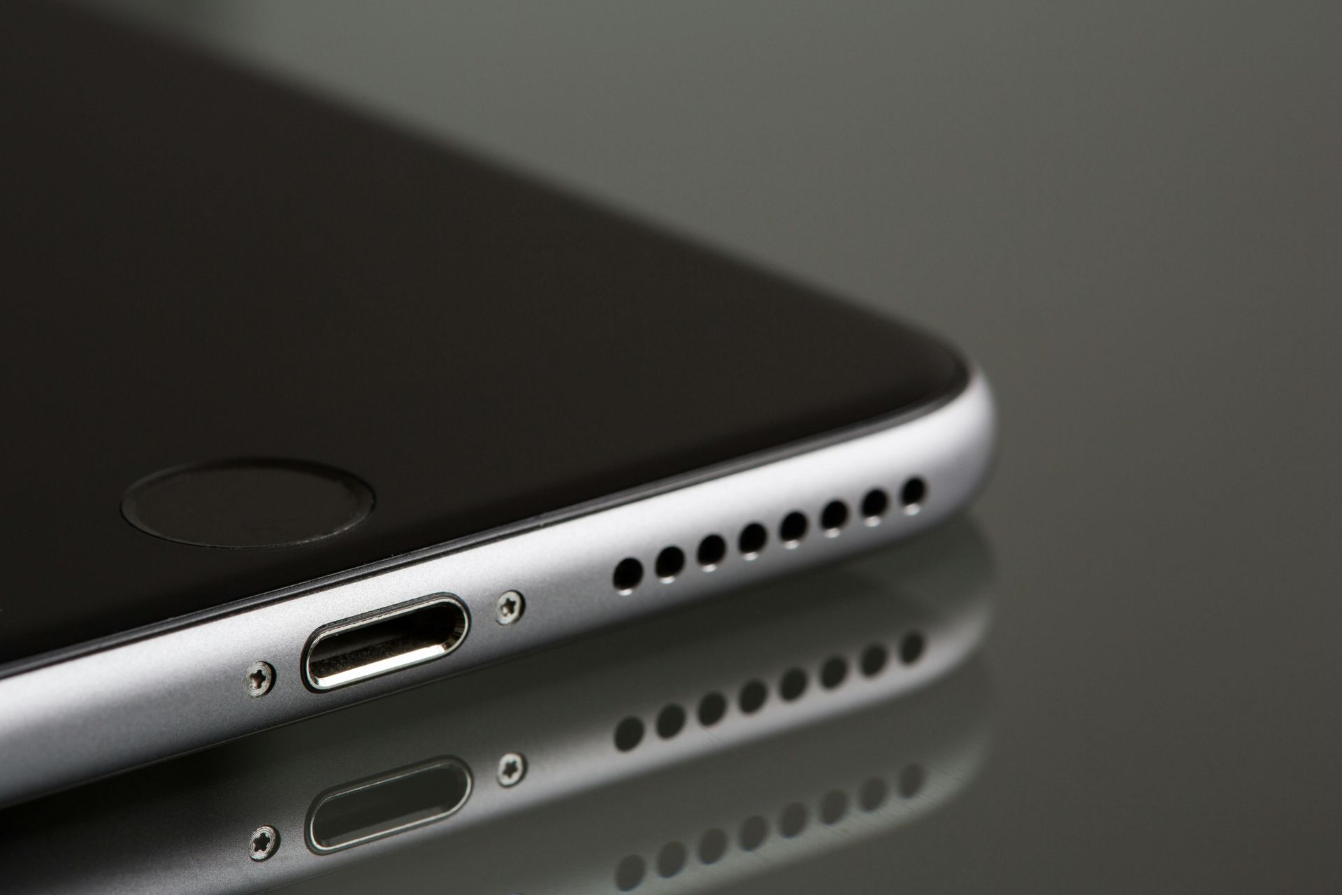A close up of the bottom of an iphone on a table.