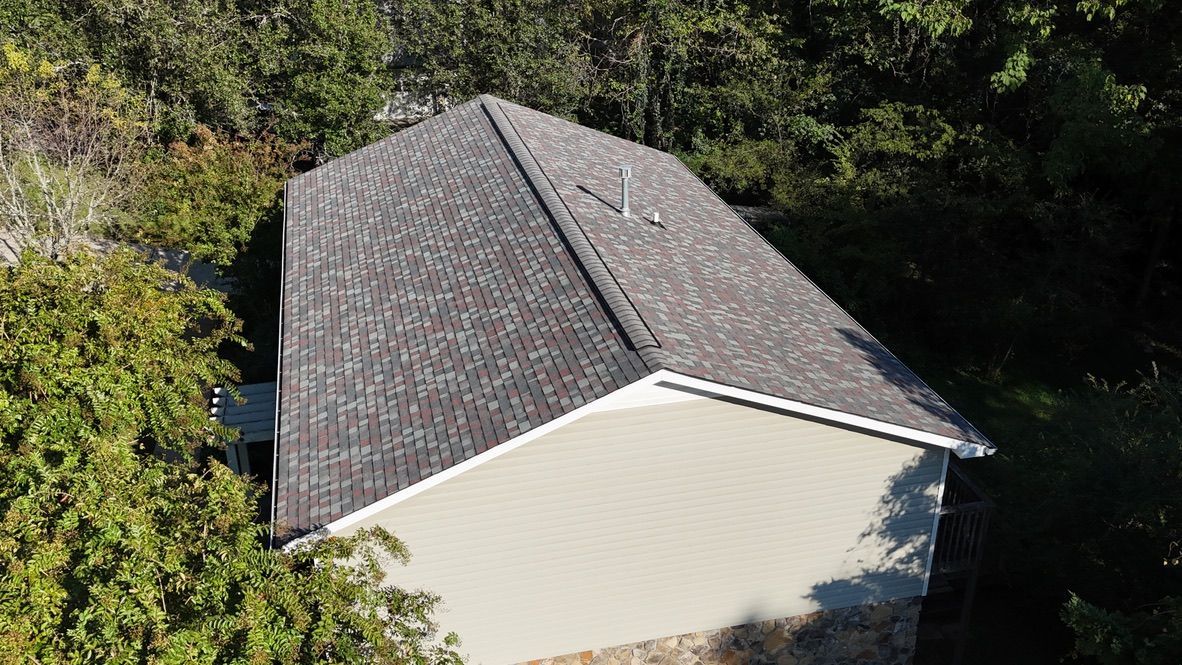 An aerial view of a house with a roof that is surrounded by trees.