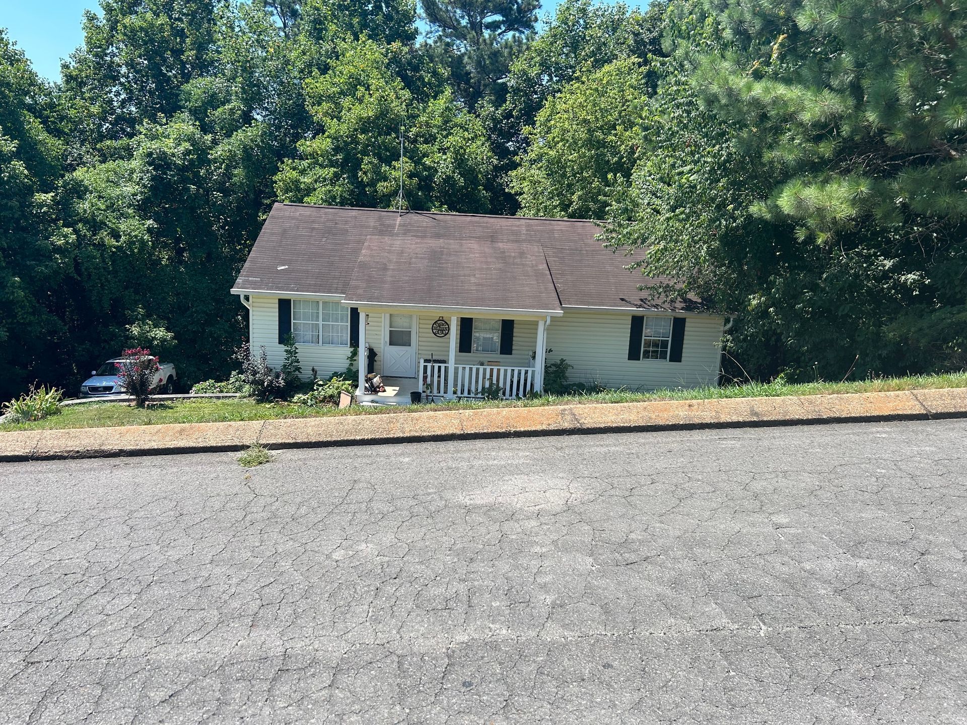 A white house with a brown roof is surrounded by trees.