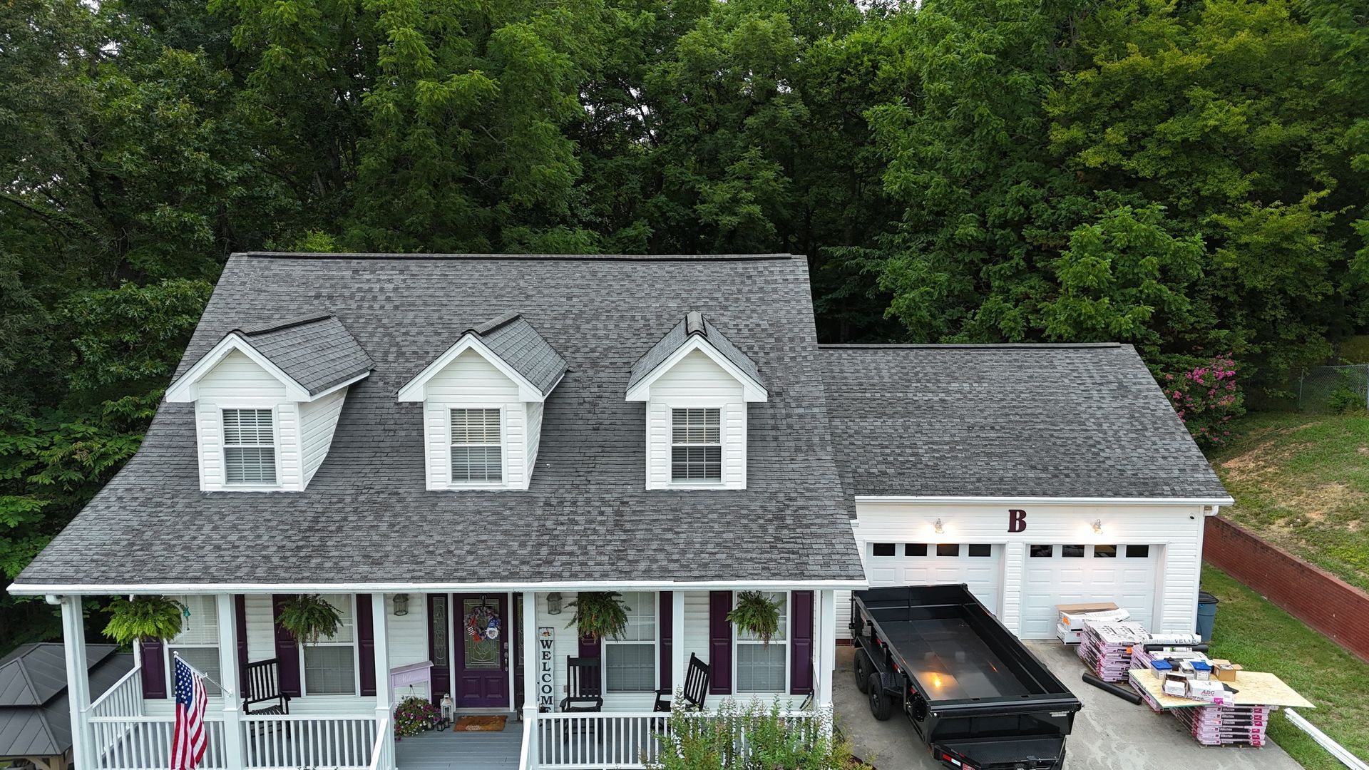 An aerial view of a house with a dumpster in front of it.