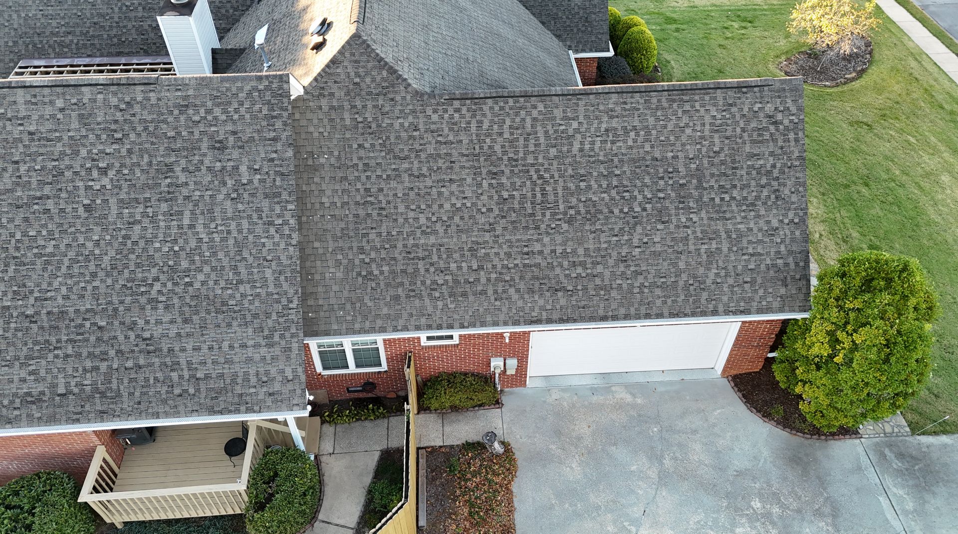 An aerial view of a brick house with a roof and a driveway.