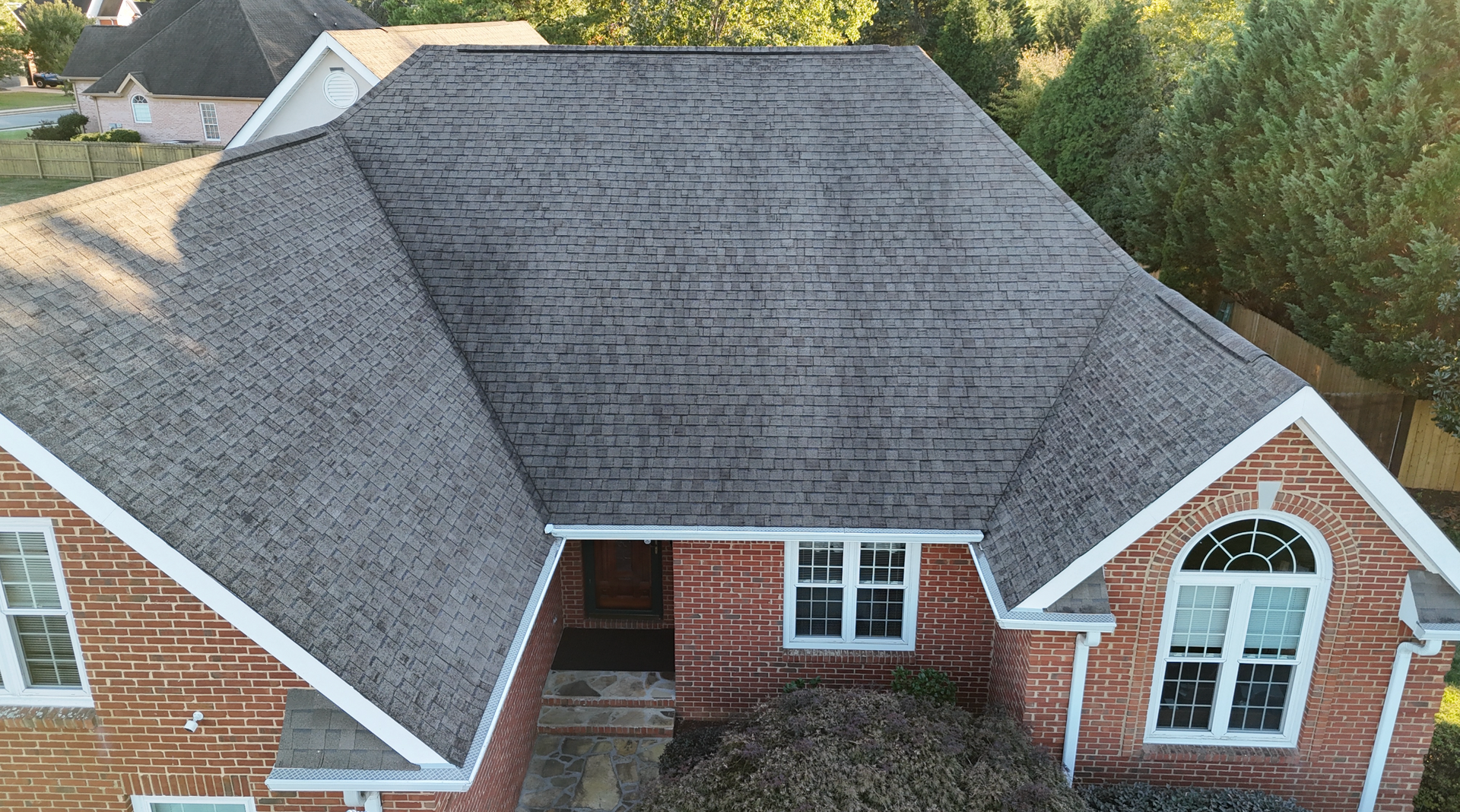 An aerial view of a brick house with a gray roof.