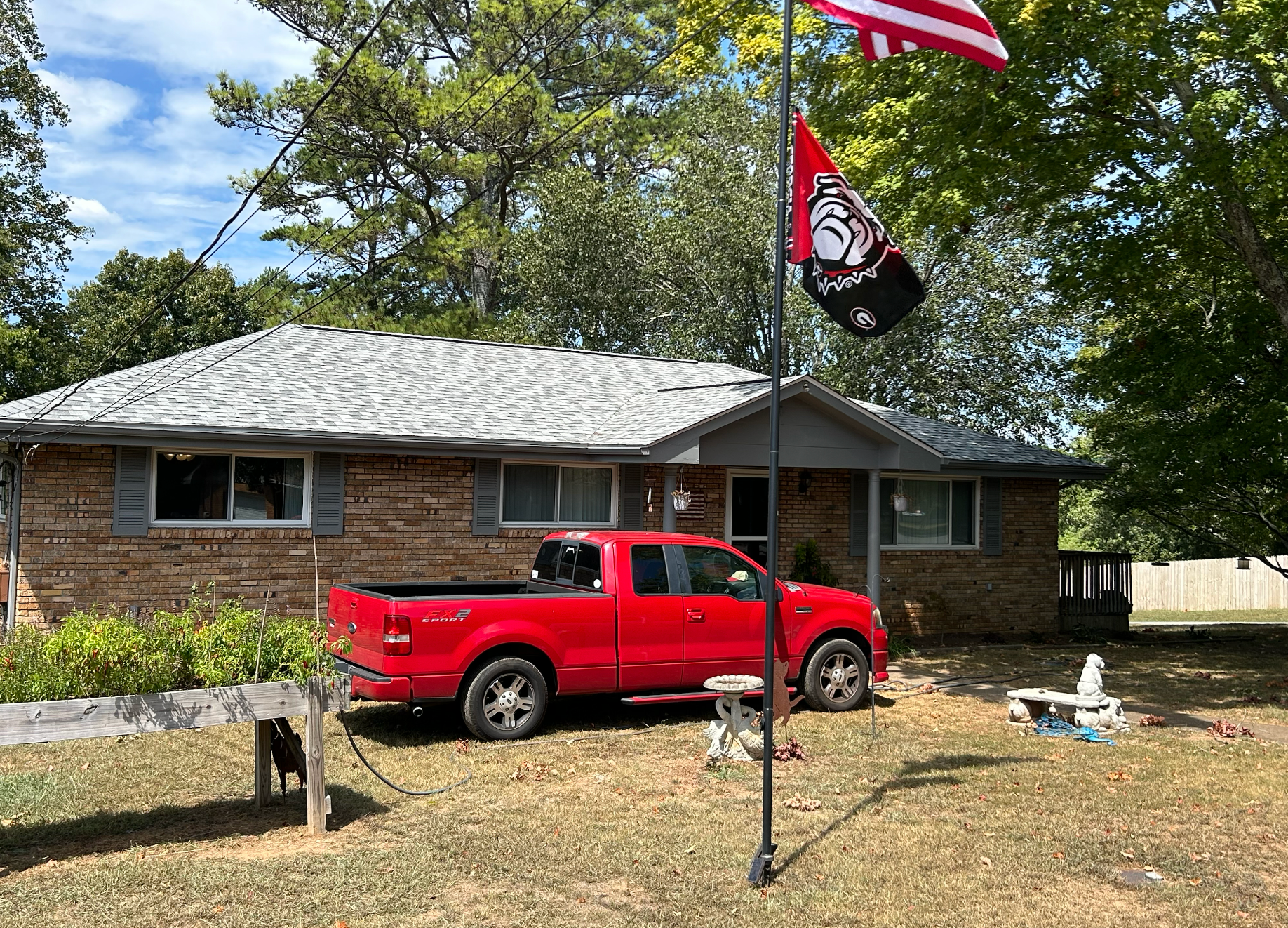 A red truck is parked in front of a brick house.