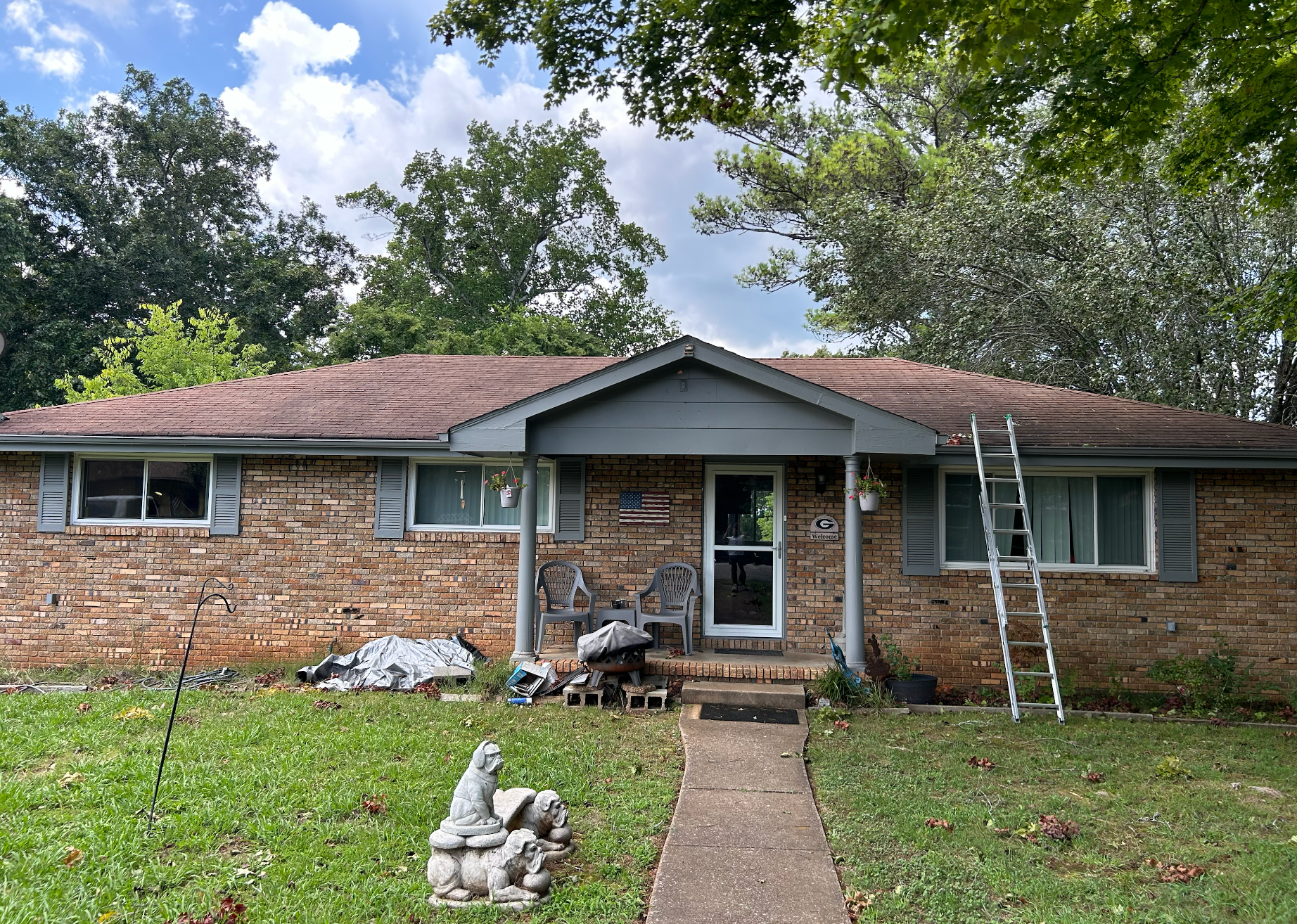 A brick house with a ladder on the front porch.