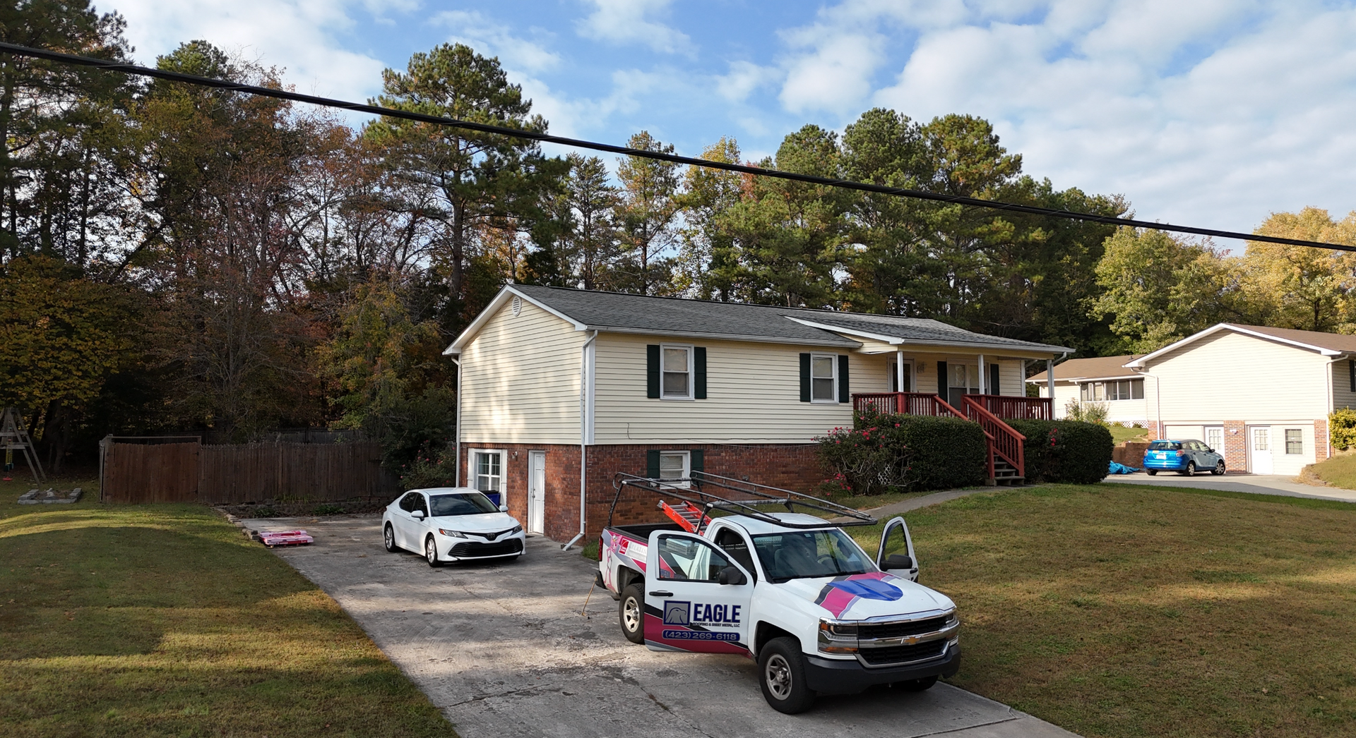 Two white trucks are parked in front of a house.