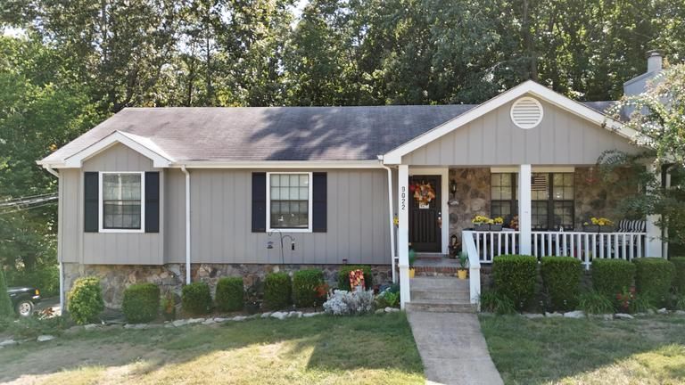 A gray house with black shutters and a porch