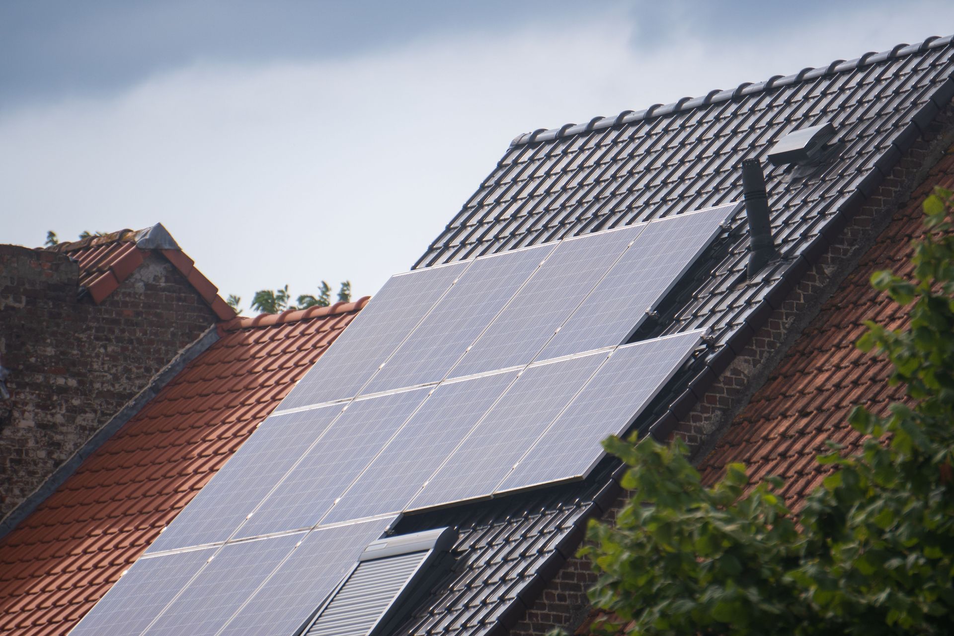 Solar panels installed on a red-tiled rooftop under an overcast sky