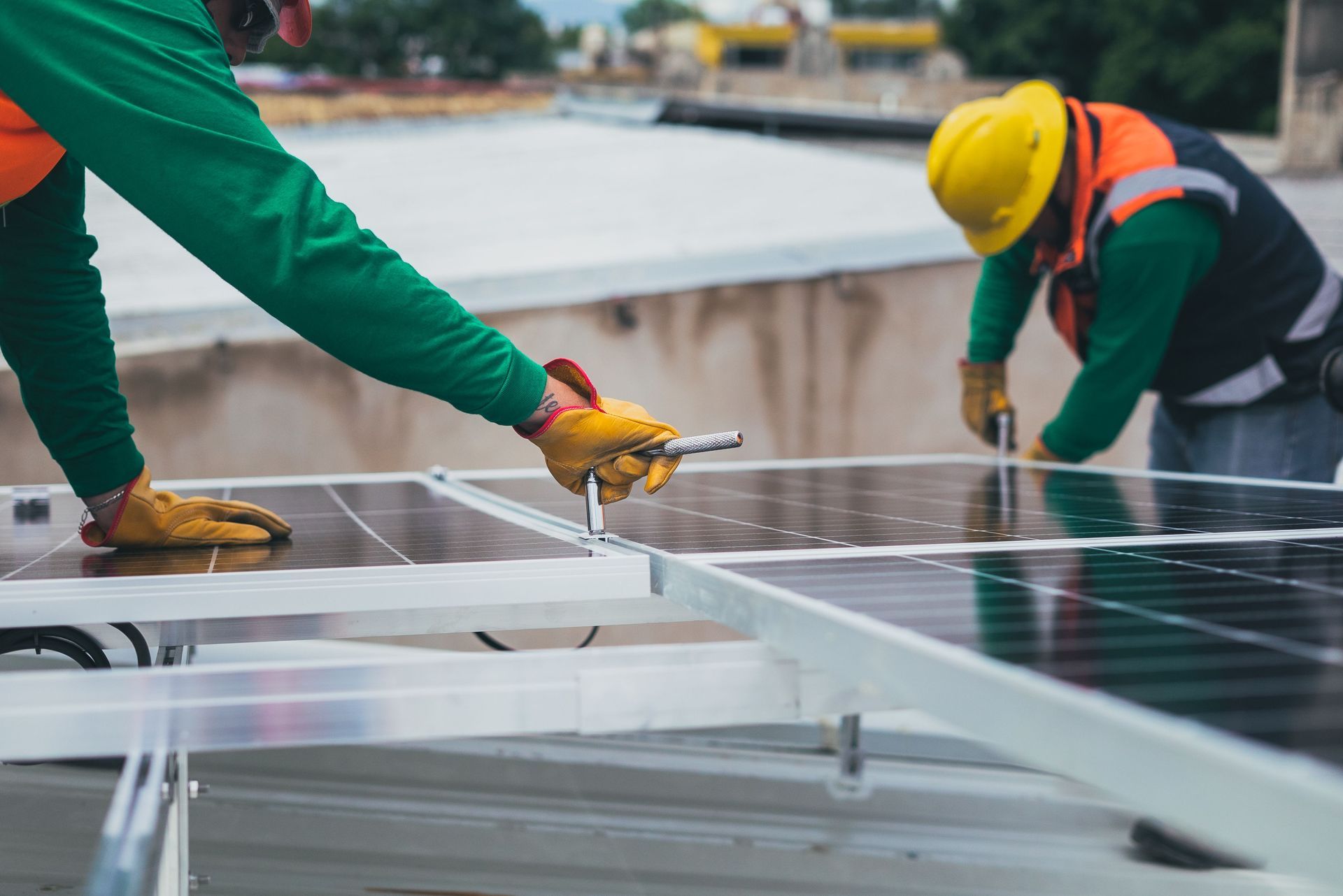 Workers installing solar panels on a rooftop with tools and safety gear
