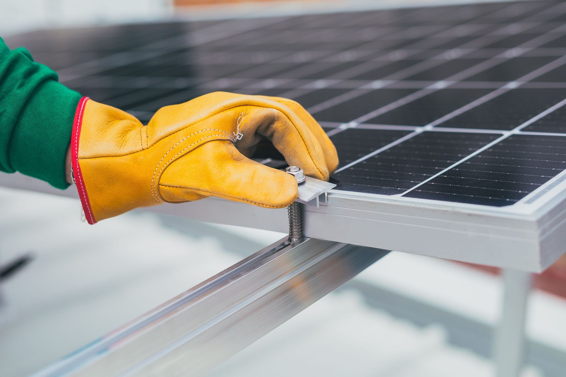 Gloved hand tightening a solar panel frame with a wrench during installation