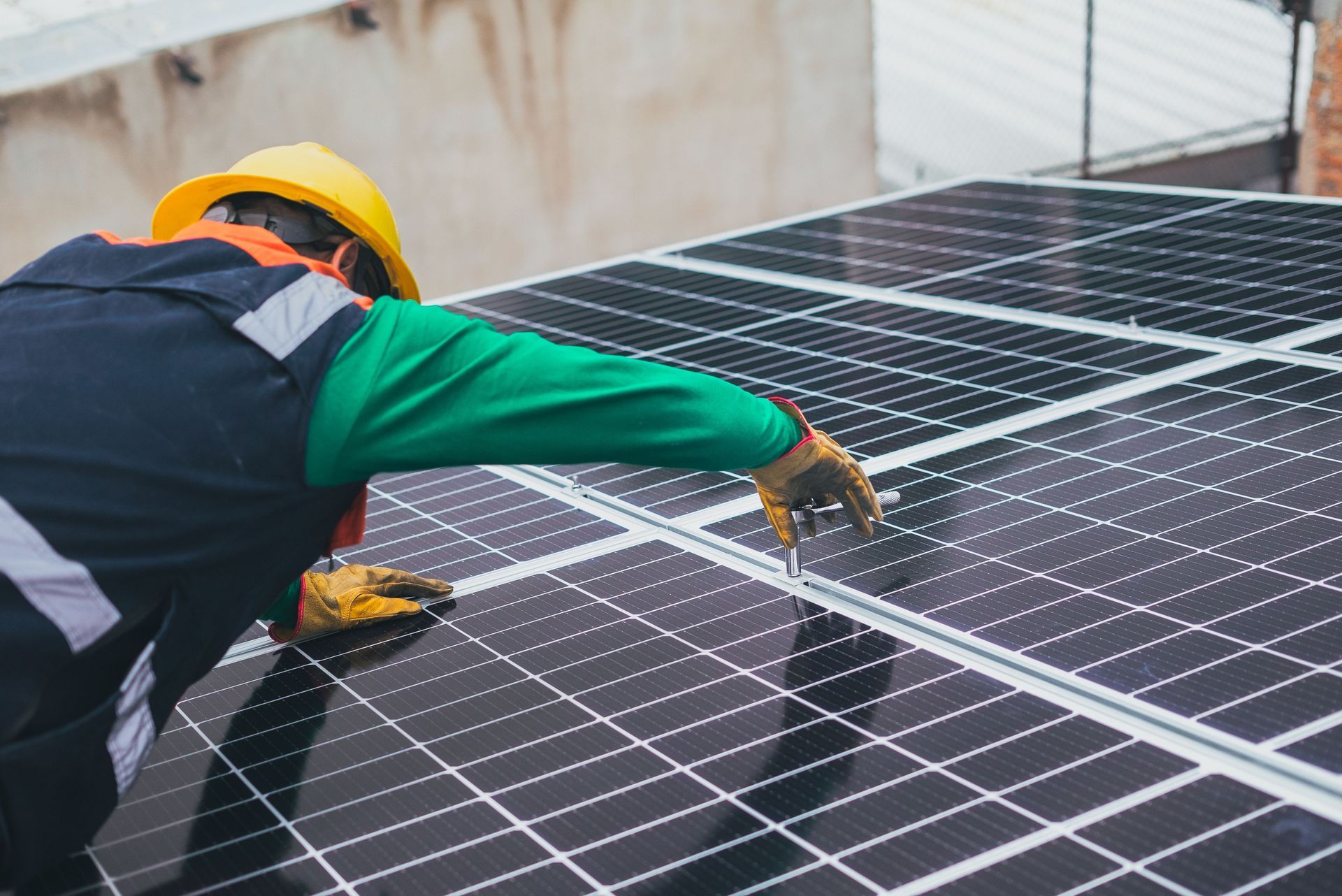 Worker in yellow hard hat cleaning solar panels on a rooftop