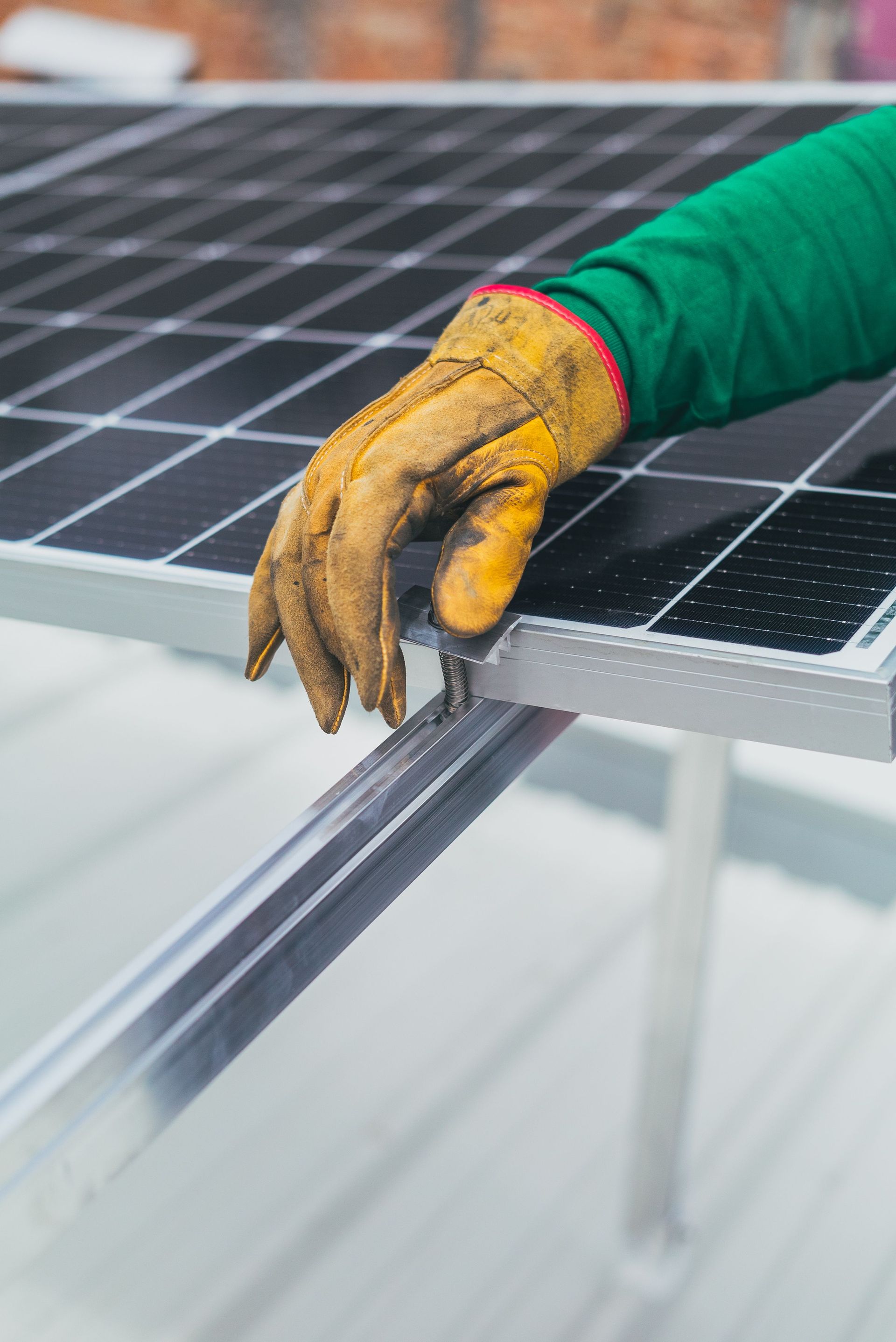 Gloved hand adjusting a solar panel frame on a rooftop panel array