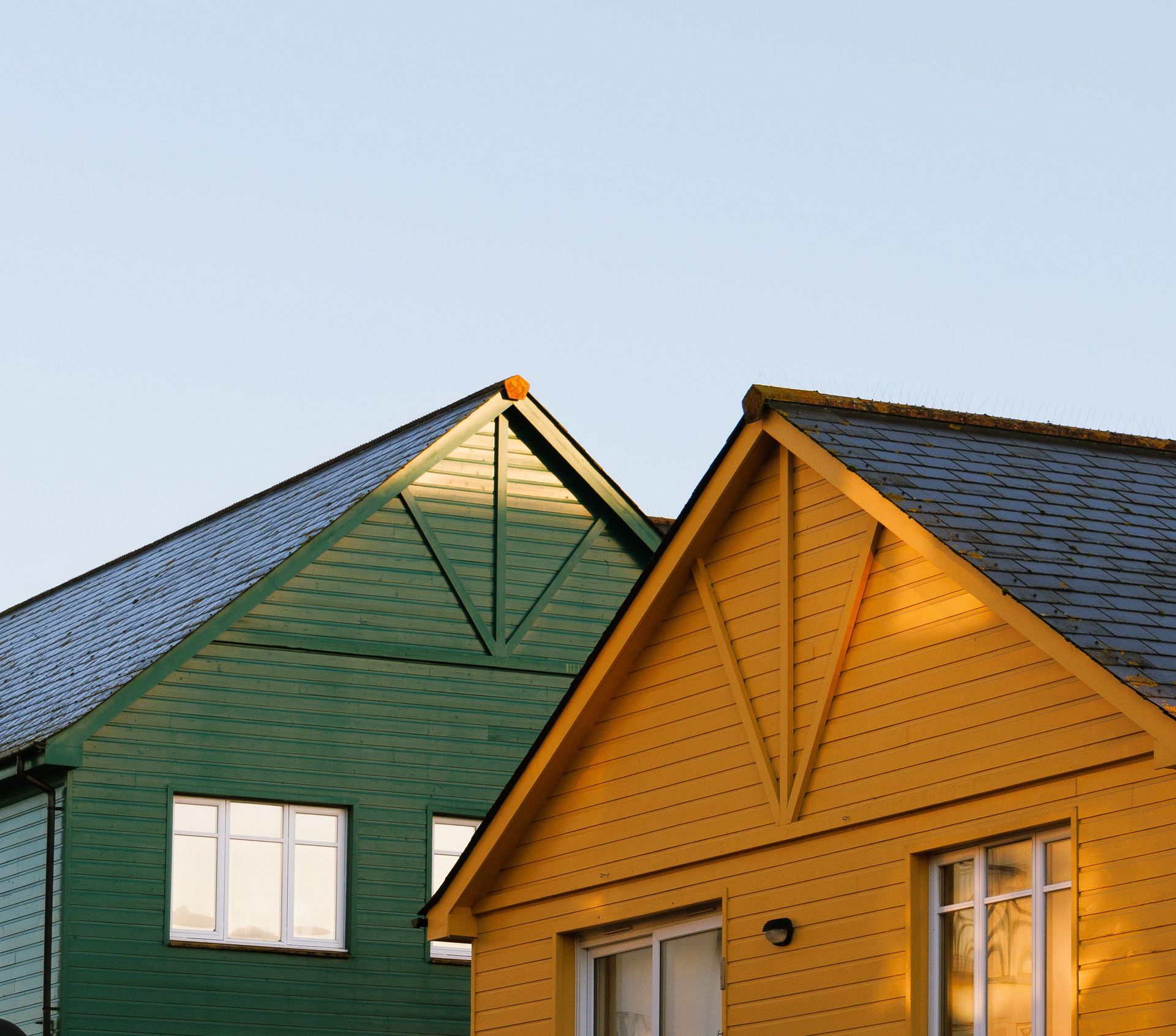 Two colorful house gables, one green and one yellow, against a clear sky