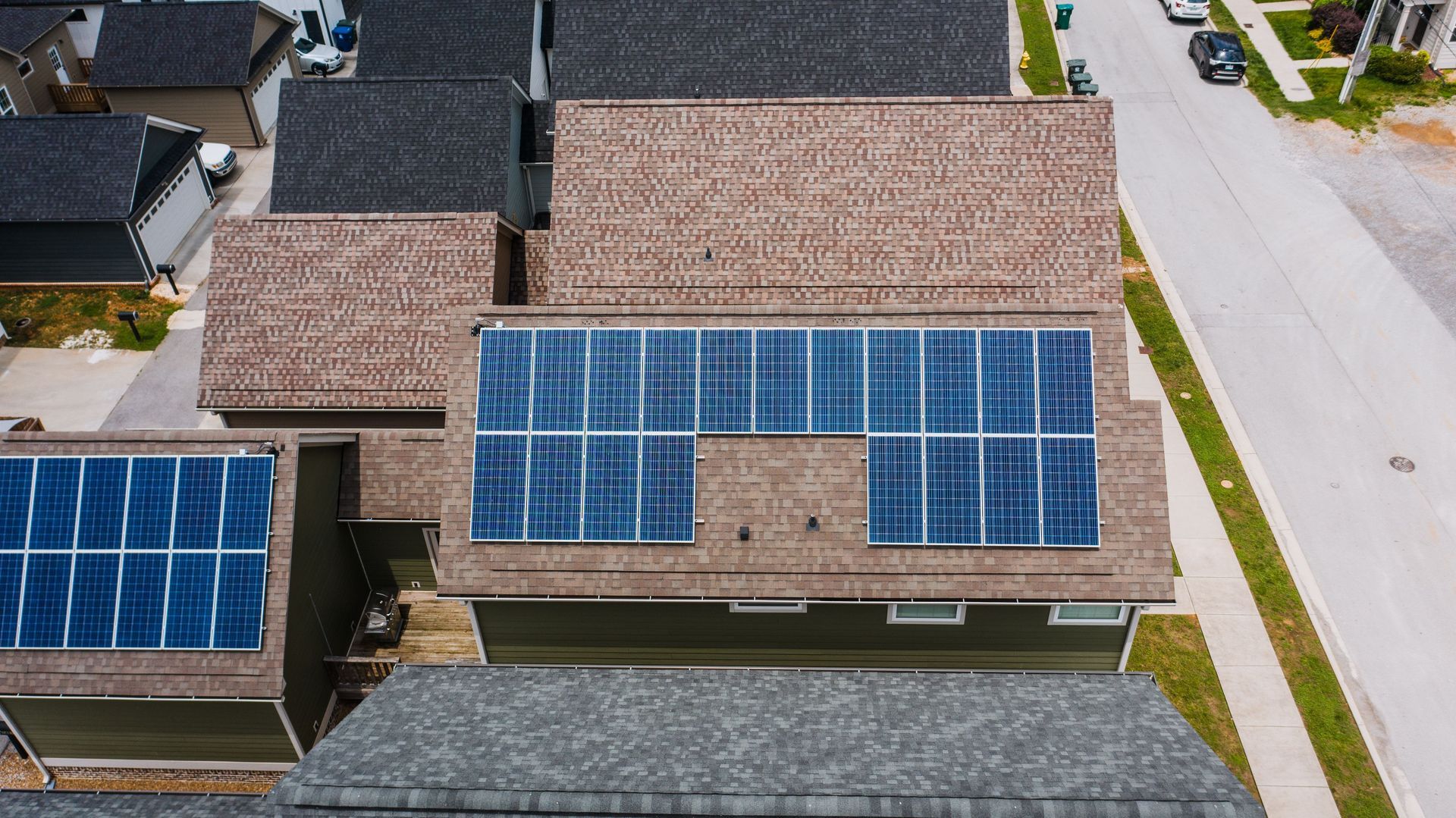 Aerial view of a suburban house roof covered with blue solar panels