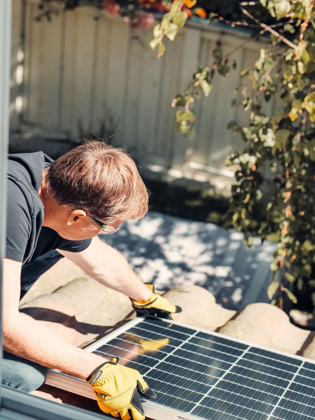 Person using yellow gloves to clean a solar panel outdoors in sunlight
