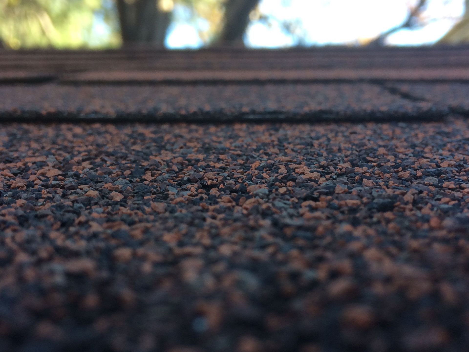 Close-up of rough asphalt pavement with a blurred horizon and warm light in the background