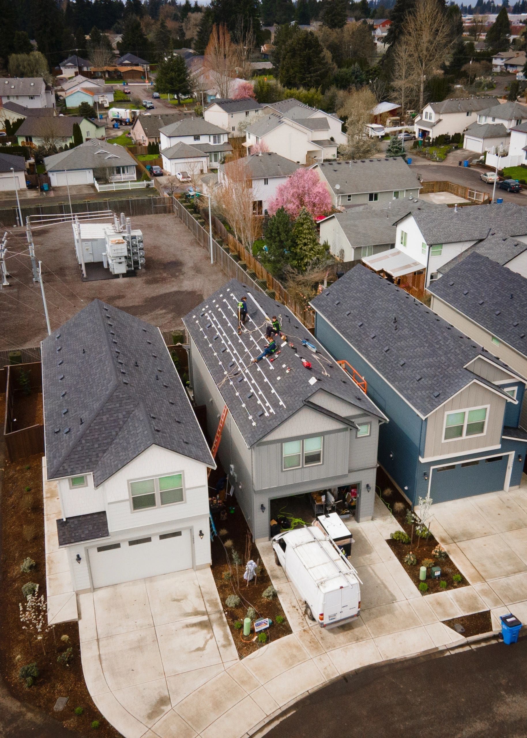 Aerial view of suburban houses on a cul-de-sac, with parked cars and one blooming pink tree
