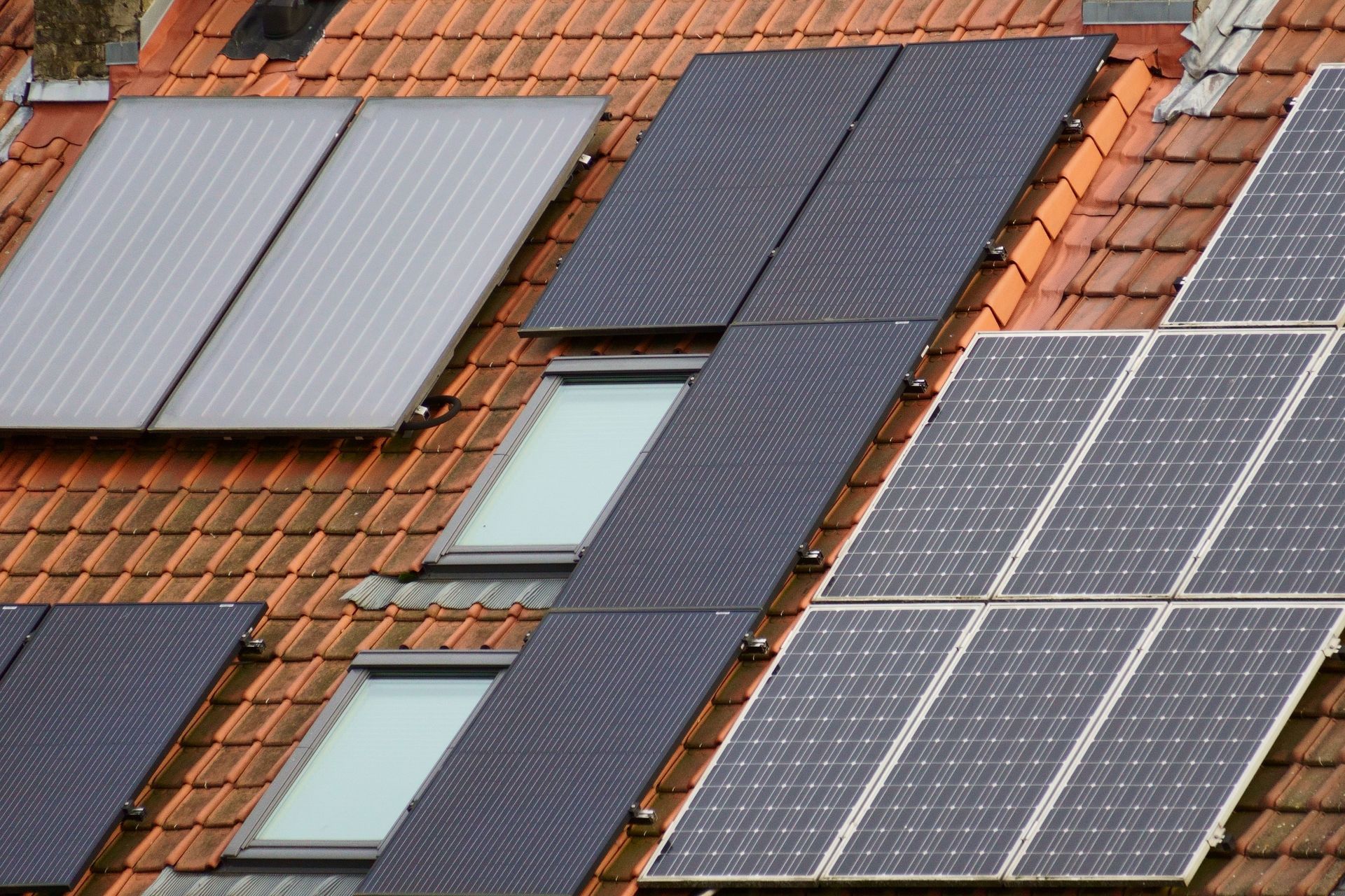 Solar panels and roof windows on a red tiled house roof