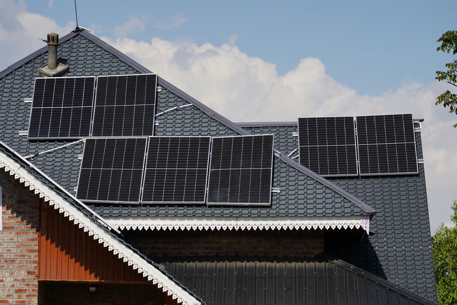 House roof with multiple solar panels under a blue sky