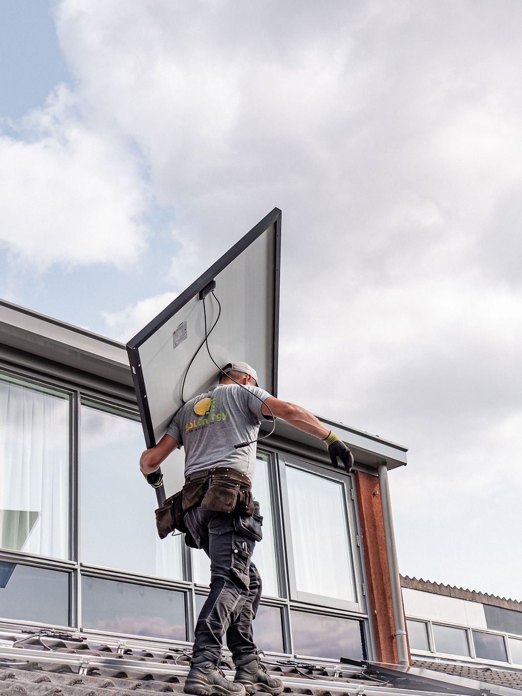 Worker installing a large sign on the side of a building under a cloudy sky
