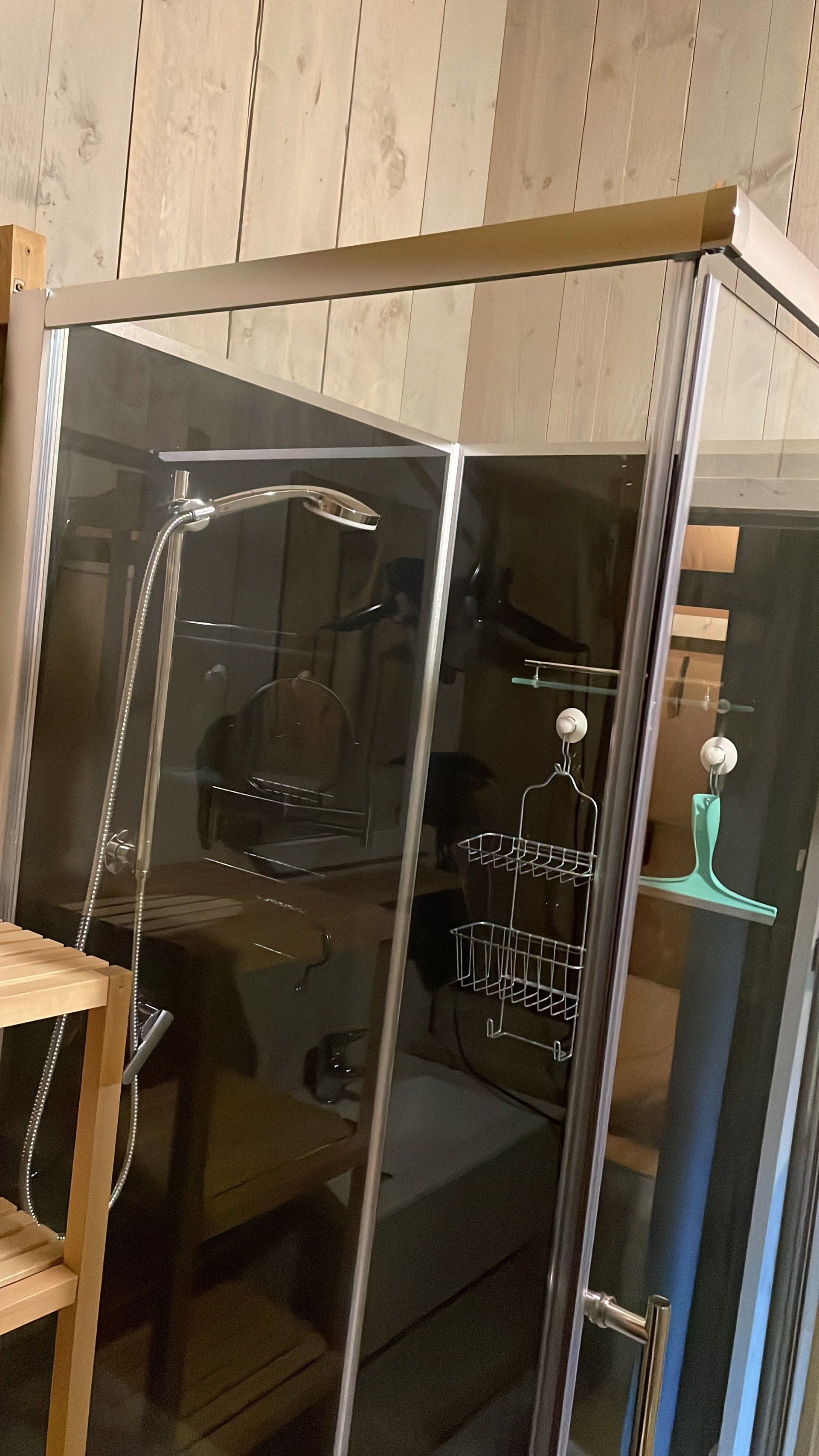 Een badkamer met een douchecabine en een houten plank.