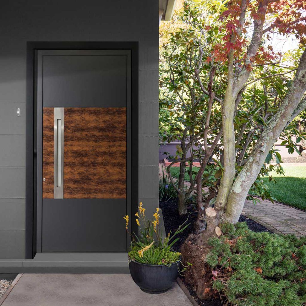 Porta d’ingresso moderna con inserto in pannello di legno, accanto a un giardino curato e a un albero